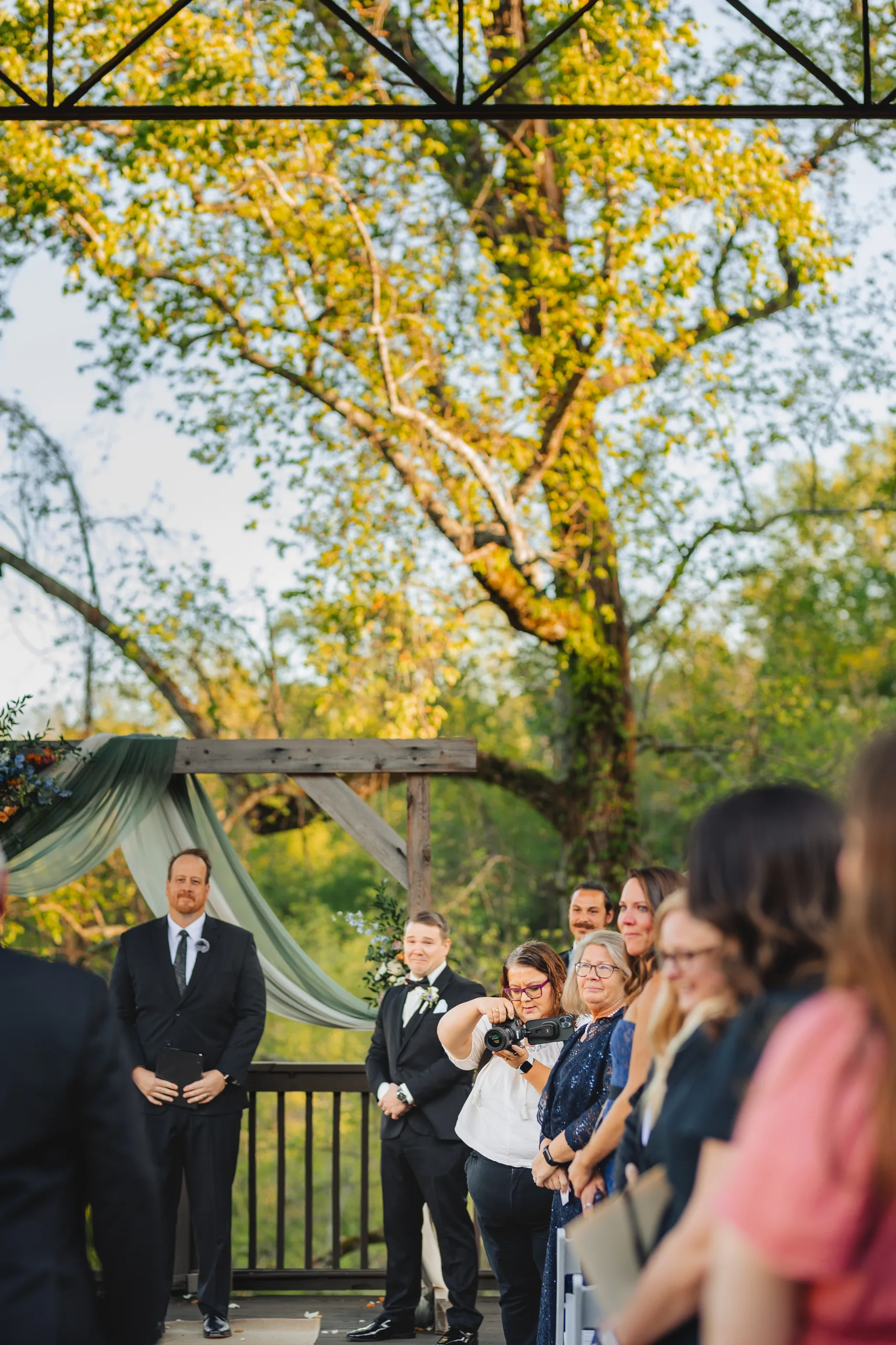 Wedding Ceremony: guests watching the ceremony under the trees at their wedding at Ivy Hall at Roswell Mill in Roswell, GA