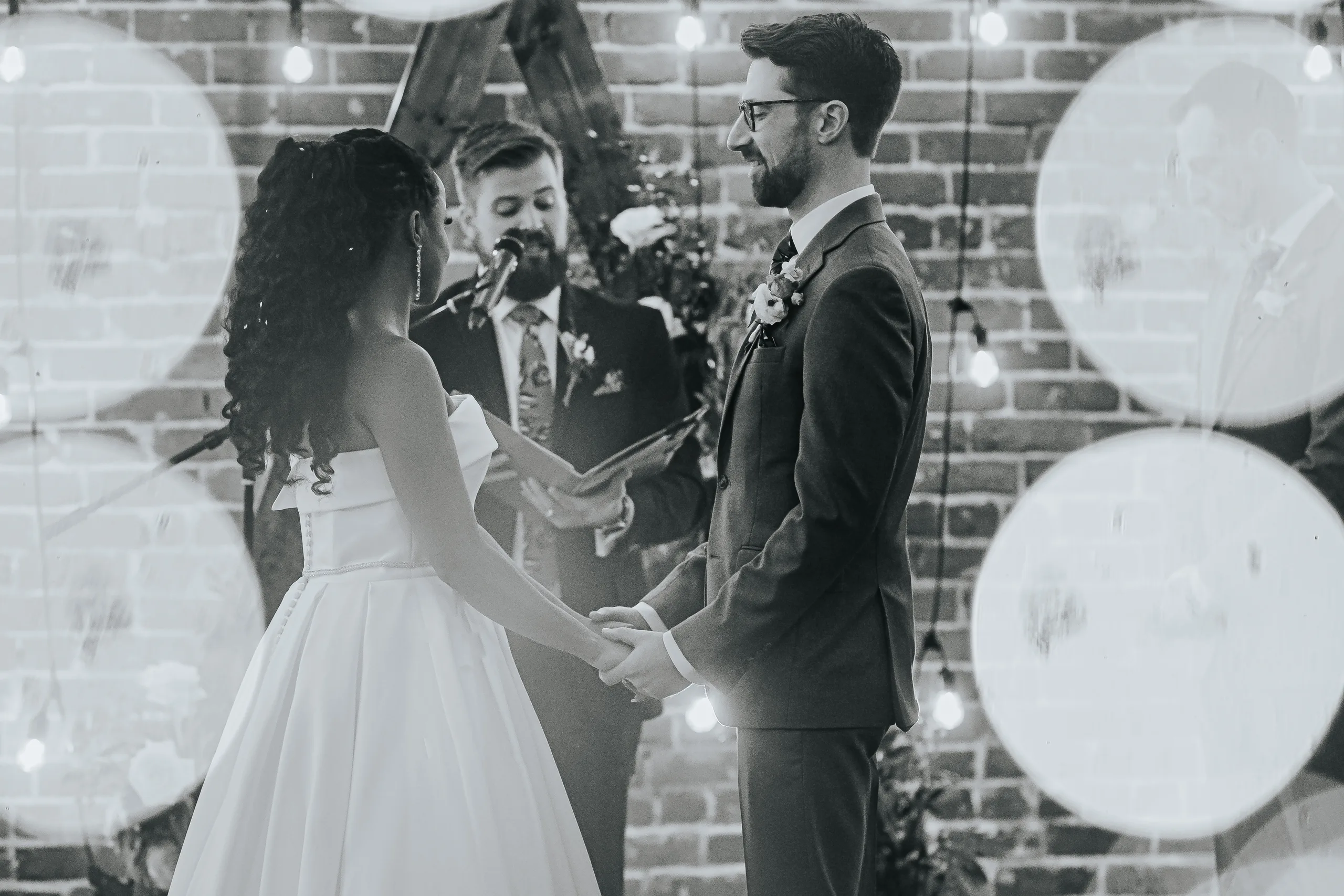 Wedding Ceremony: holding hands during the vows, in black and white, at their wedding at Terminus 330 in Atlanta, GA