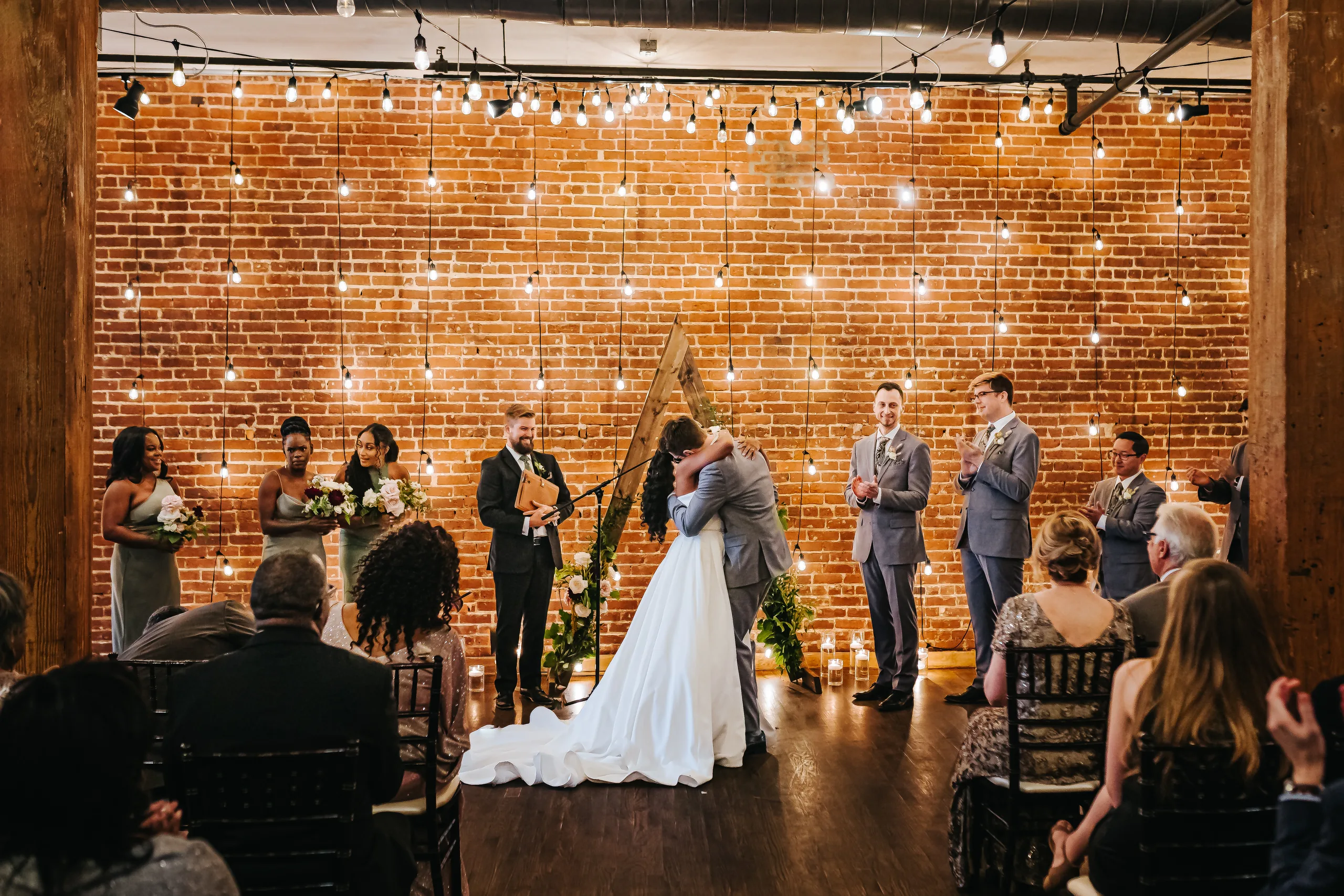 Wedding Ceremony: the first kiss as the wedding party cheers, at their wedding at Terminus 330 in Atlanta, GA