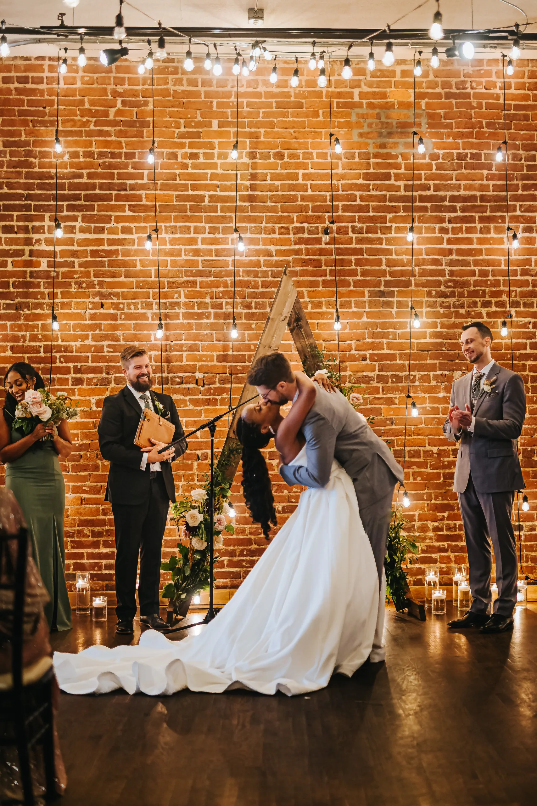 Wedding Ceremony: a dip kiss in front of the string lights, at their wedding at Terminus 330 in Atlanta, GA