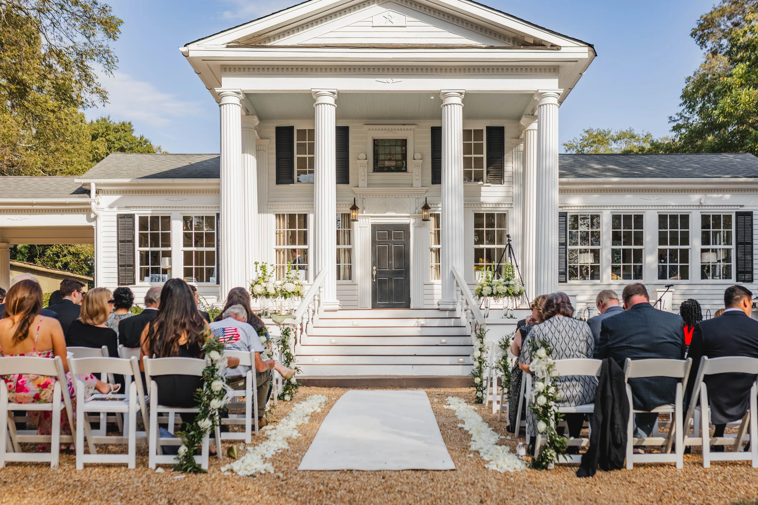 Wedding Ceremony: guests seated on the lawn facing the columns, at their wedding at Naylor Hall in Roswell, GA