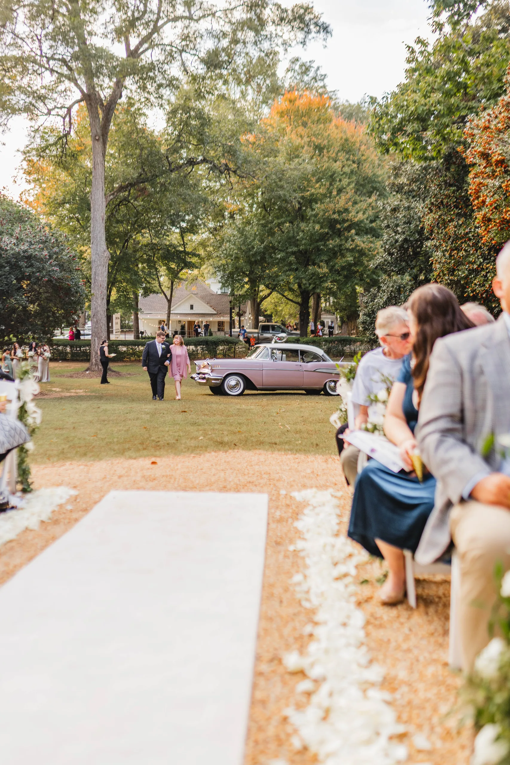Wedding Ceremony: the bride walking across the lawn from the pink Chevrolet, at their wedding at Naylor Hall in Roswell, GA