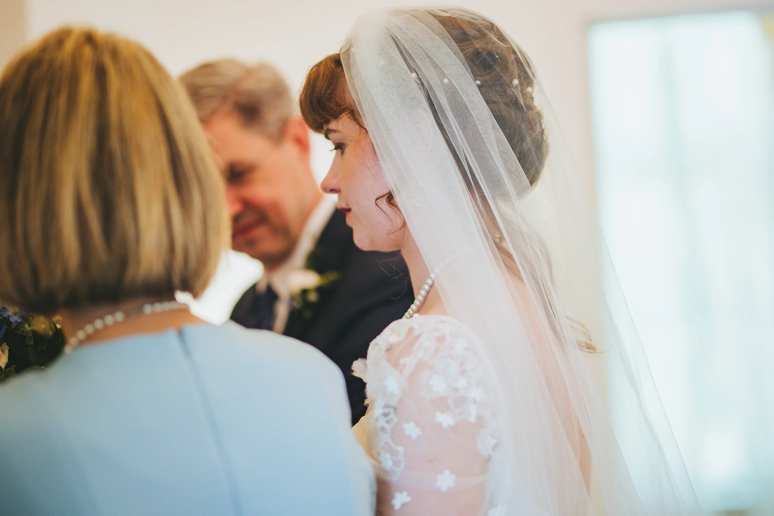 Wedding Ceremony: the bride under her veil beside her mom and dad, at their wedding at the Chapel at Simpsonwood Park in Peachtree Corners, GA