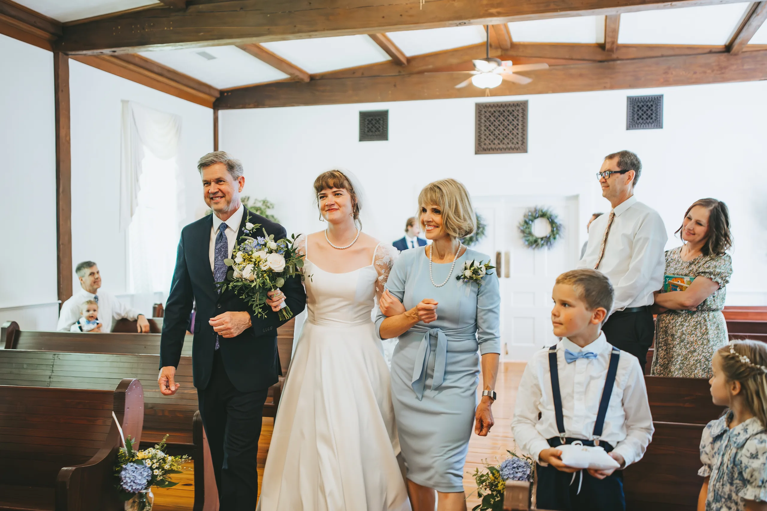 Wedding Ceremony: the bride walking down the aisle with her dad and mom, at their wedding at the Chapel at Simpsonwood Park in Peachtree Corners, GA