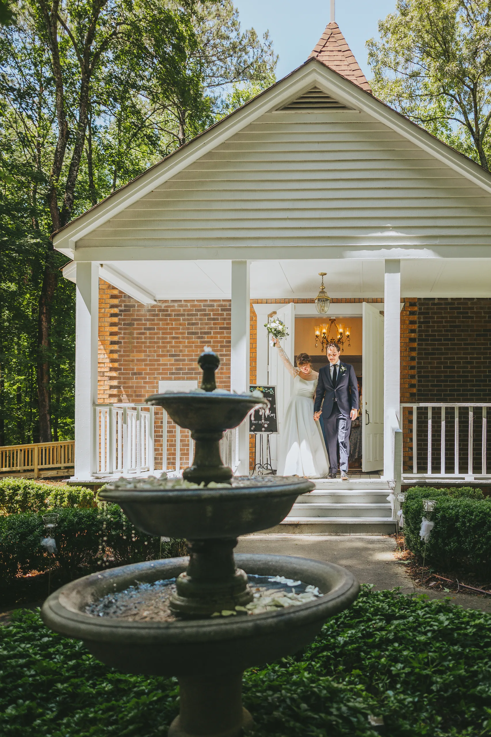Wedding Ceremony: walking out of the chapel past the fountain, at their wedding at the Chapel at Simpsonwood Park in Peachtree Corners, GA