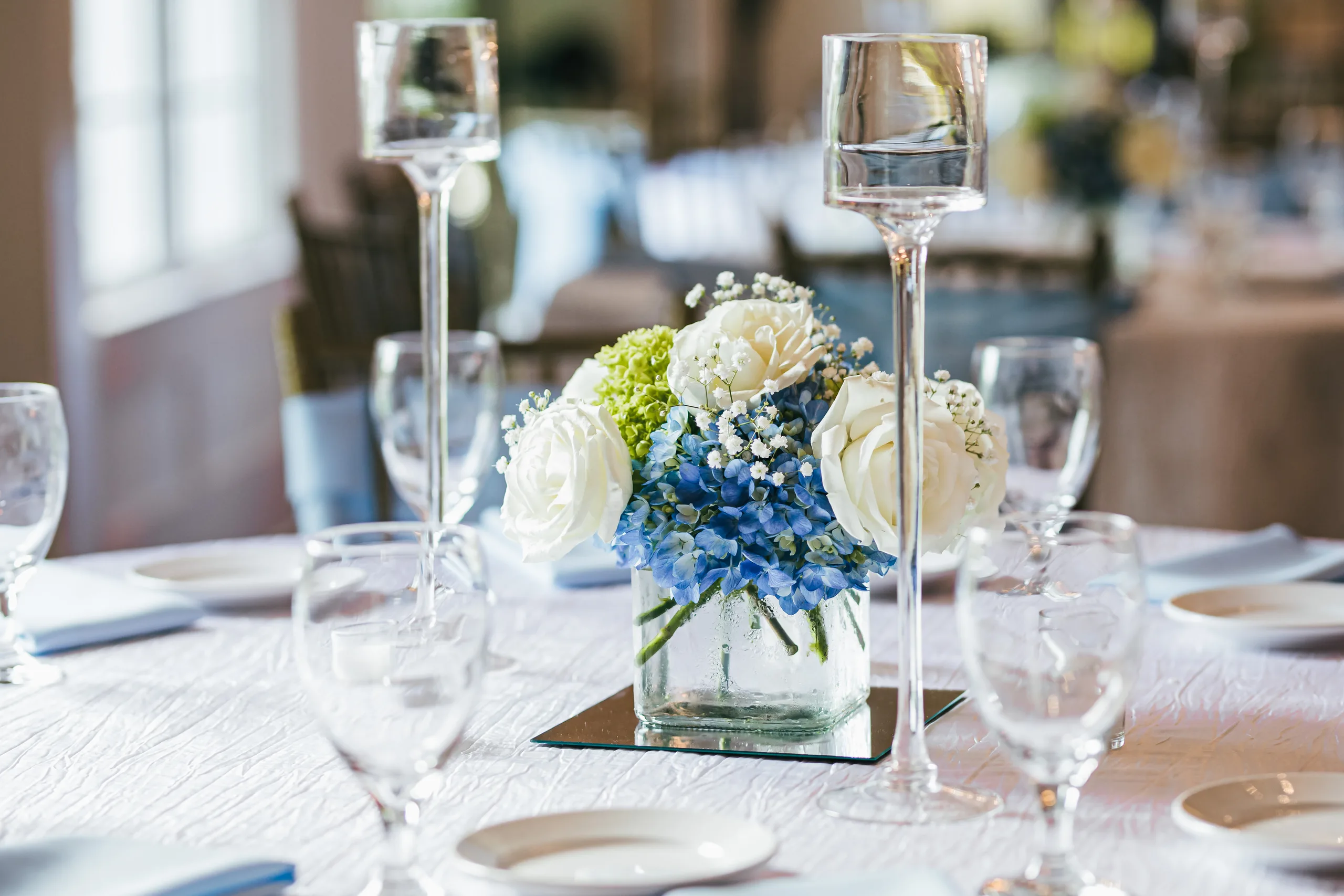 Reception Details: a centerpiece of white roses and blue hydrangea at a wedding at the Payne-Corley House in Duluth, GA
