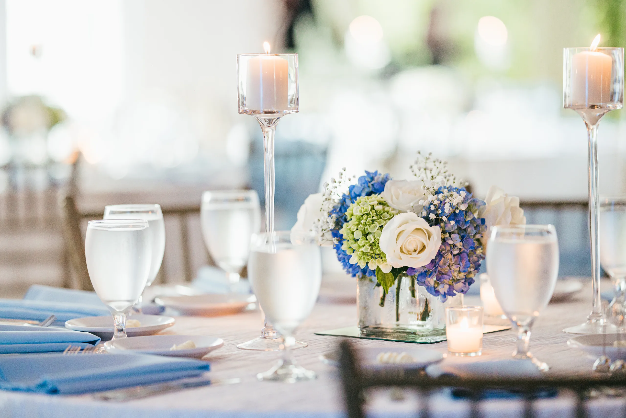Reception Details: candles and blue and white flowers on the tables at a wedding at the Payne-Corley House in Duluth, GA