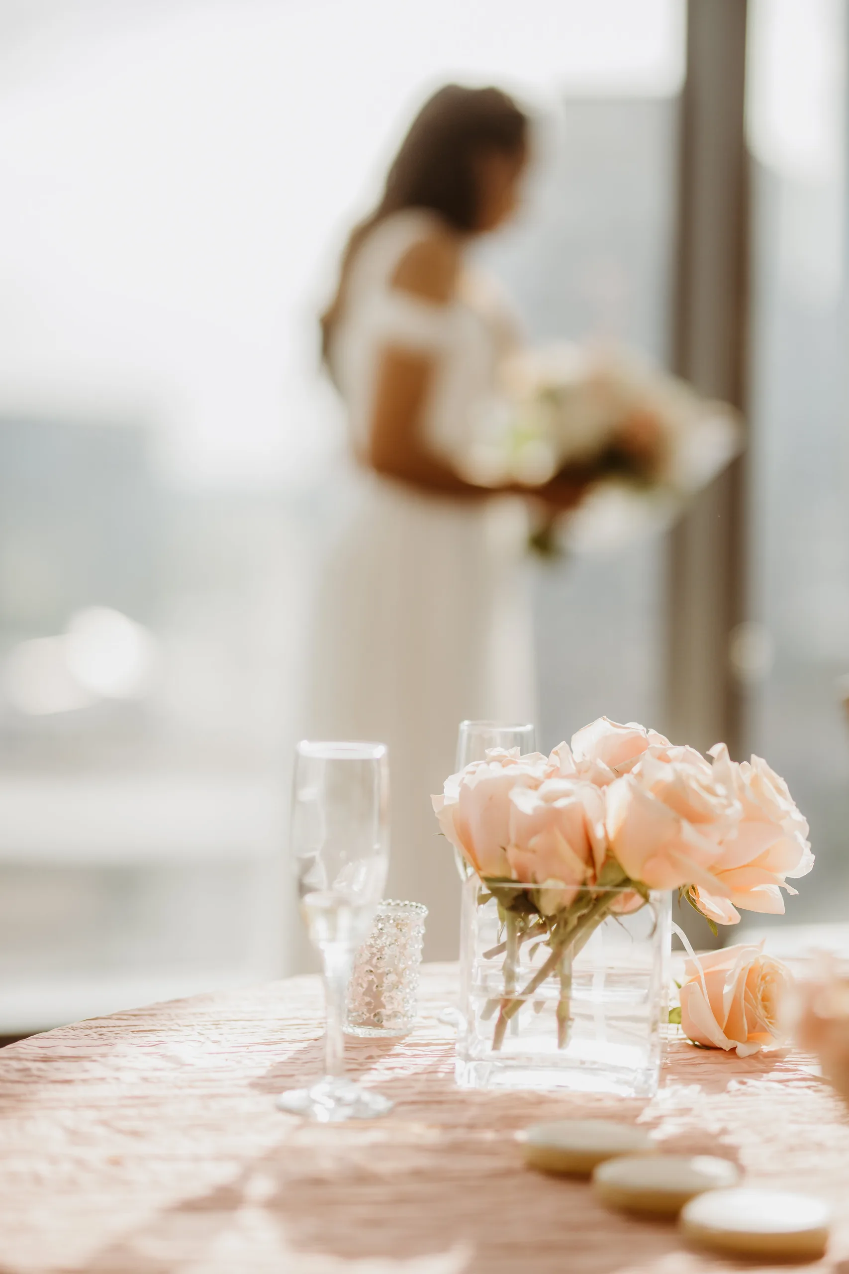Reception Details: peach roses on the table with the bride blurred behind them, at their elopement at Ventanas in Atlanta, GA