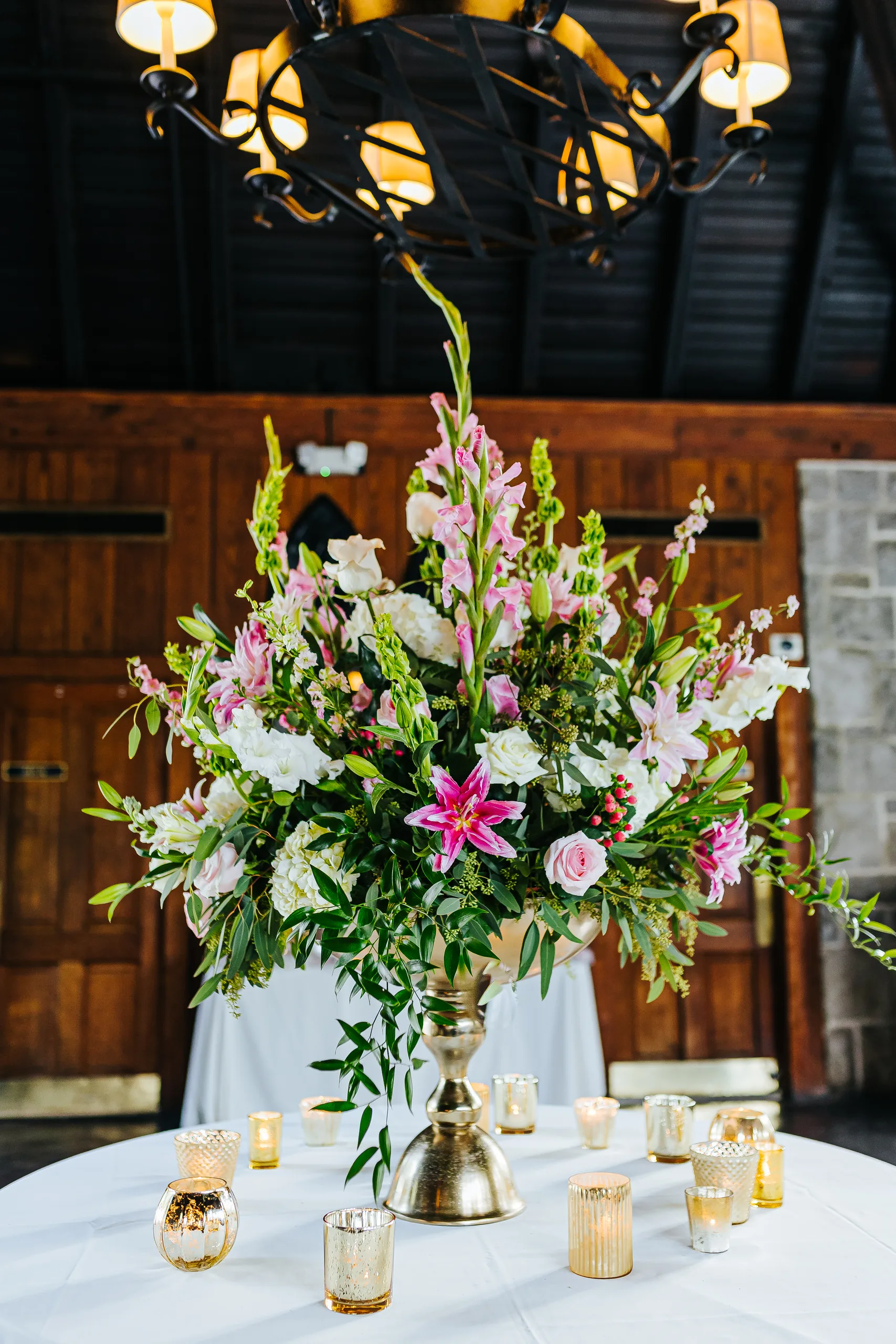 Reception Details: a tall arrangement of pink lilies and snapdragons with gold votives, at a wedding at The Piedmont Room in Atlanta, GA