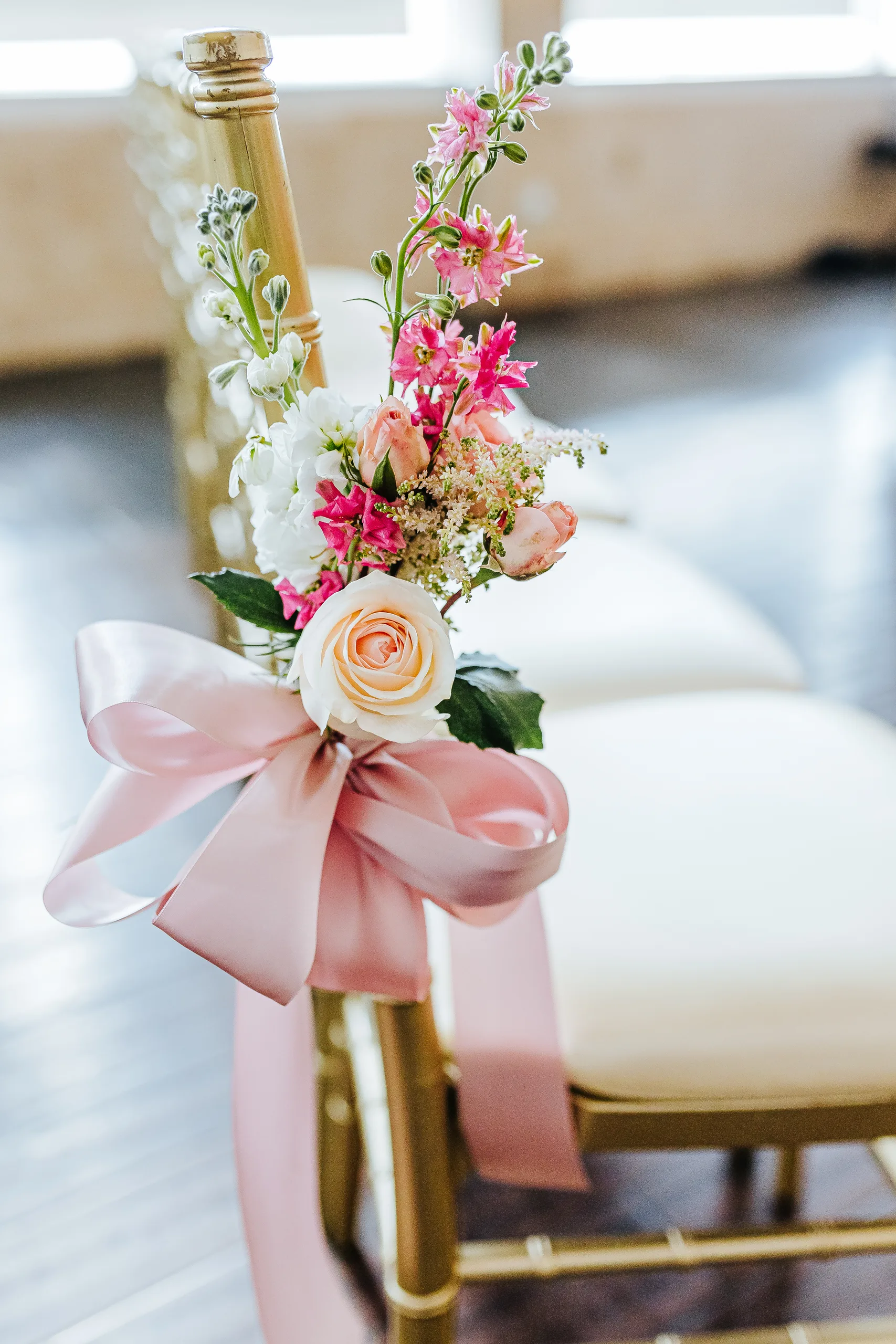 Wedding Florals: a pink rose and ribbon on a gold aisle chair, at a wedding at The Piedmont Room in Atlanta, GA