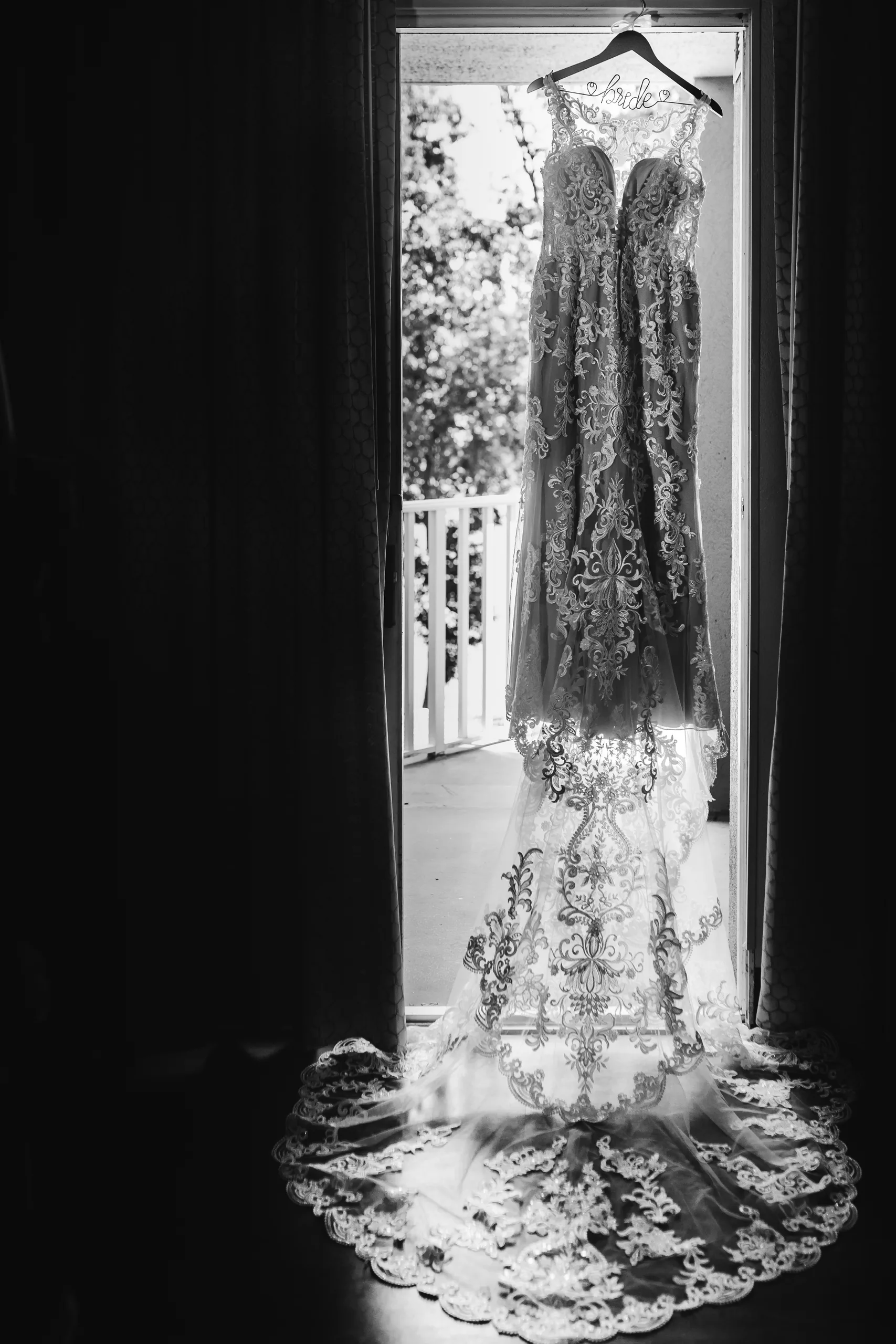 Wedding Details: her lace gown hanging in the balcony doorway, in black and white, at a wedding at Atlanta Evergreen Lakeside Resort in Stone Mountain, GA