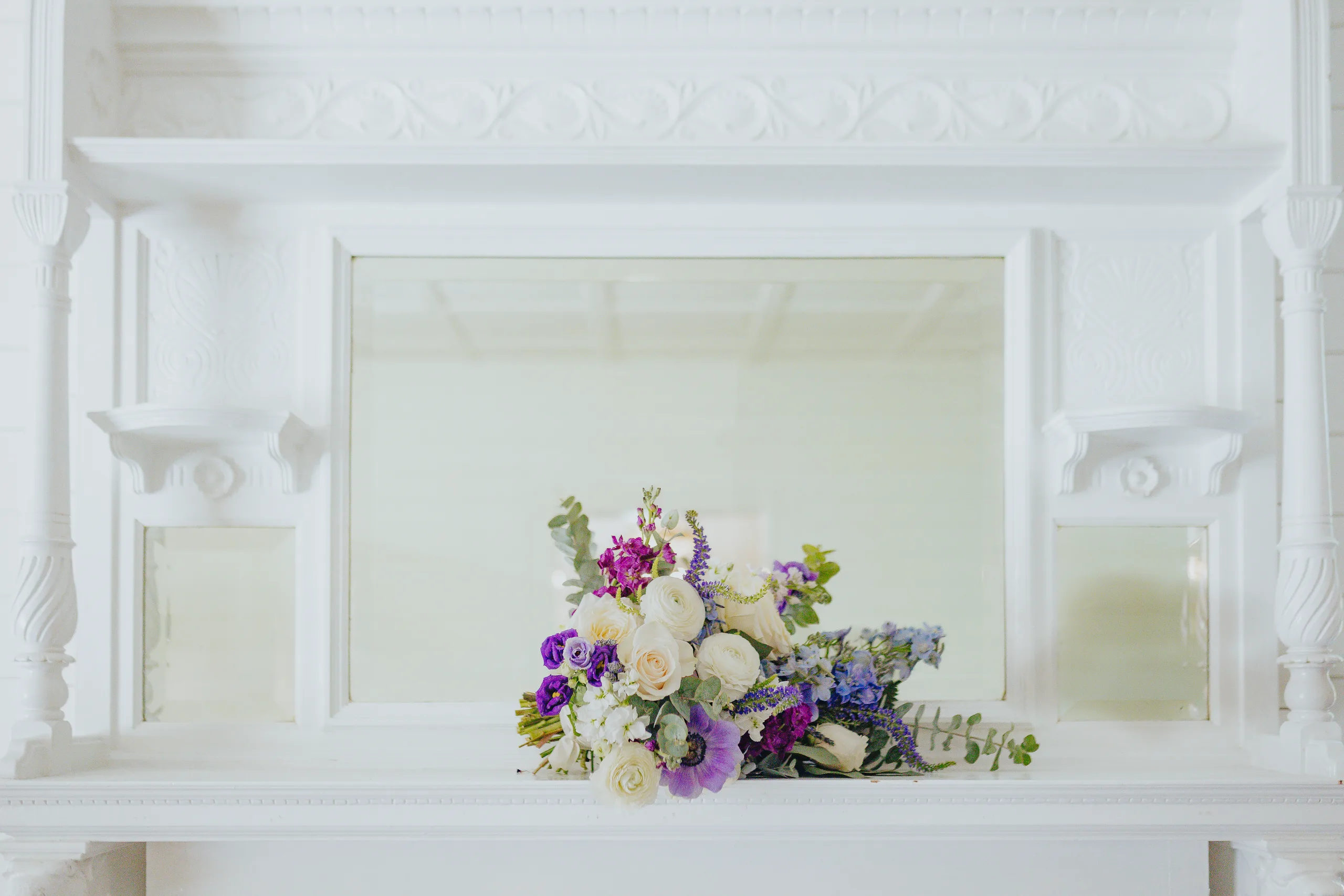 Wedding Florals: her bouquet on the white mantel, at a wedding at The Wildflower 301 in Greensboro, GA