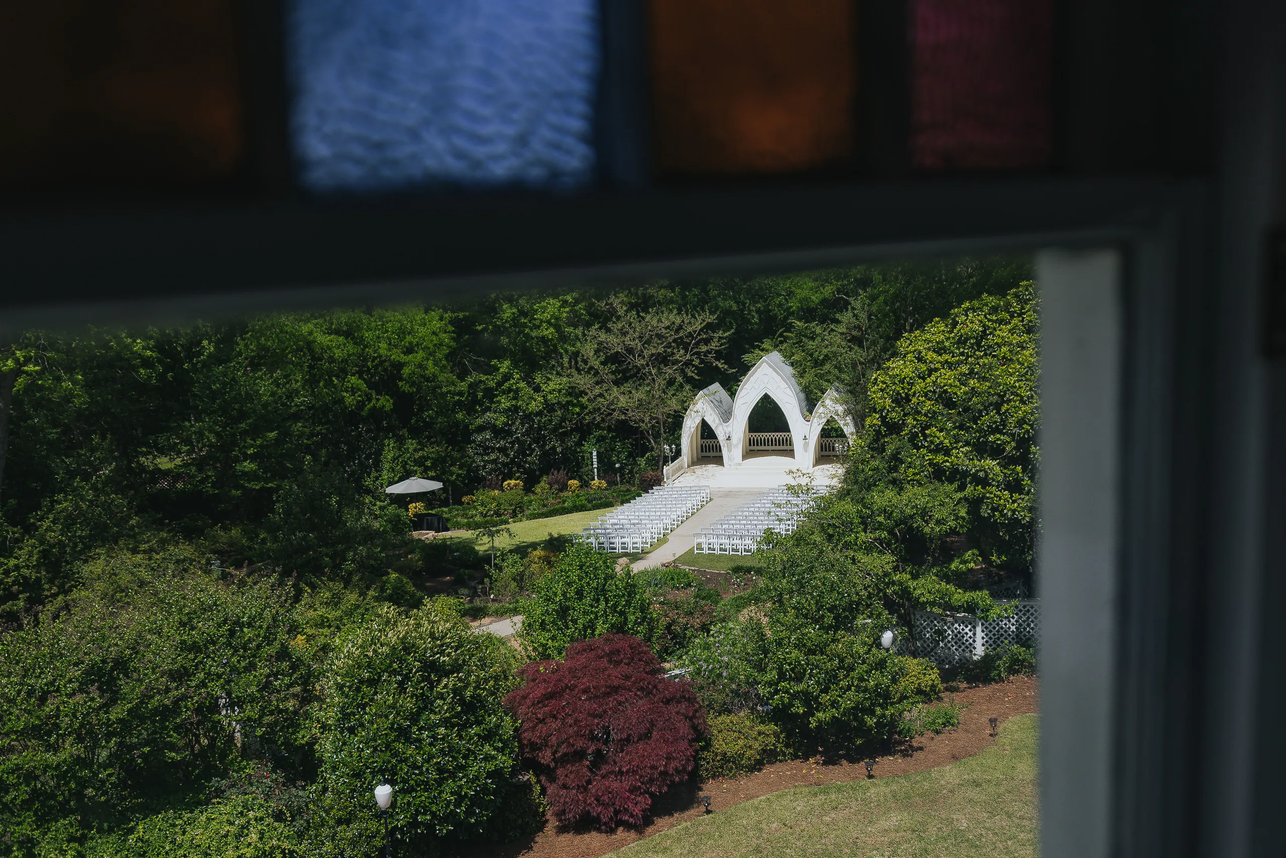 Wedding Ceremony: the outdoor chapel seen through a stained glass window, at a wedding at The Wildflower 301 in Greensboro, GA