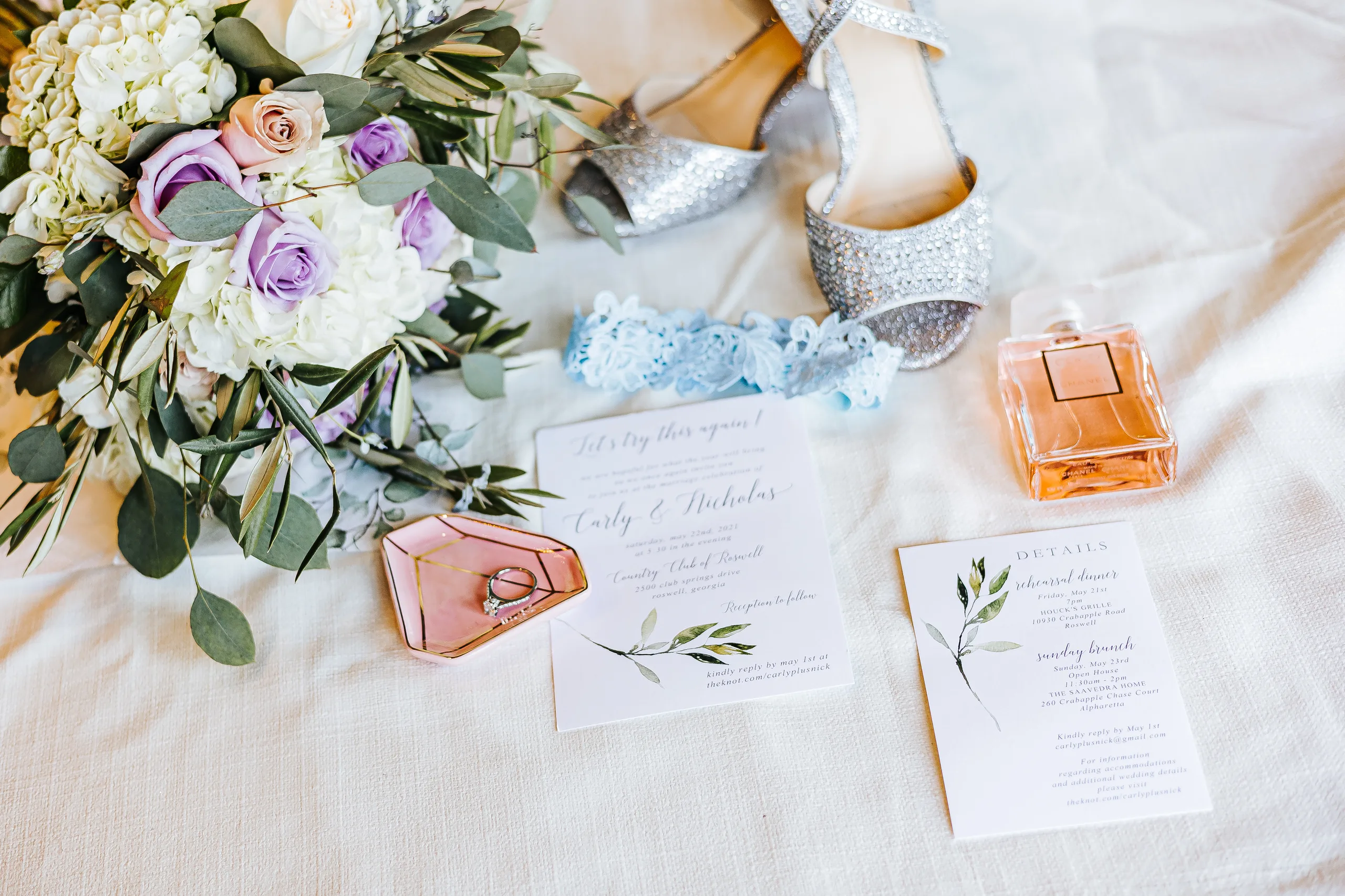 Wedding Details: the invitation, bouquet, heels, garter and perfume at a wedding at the Country Club of Roswell in Roswell, GA