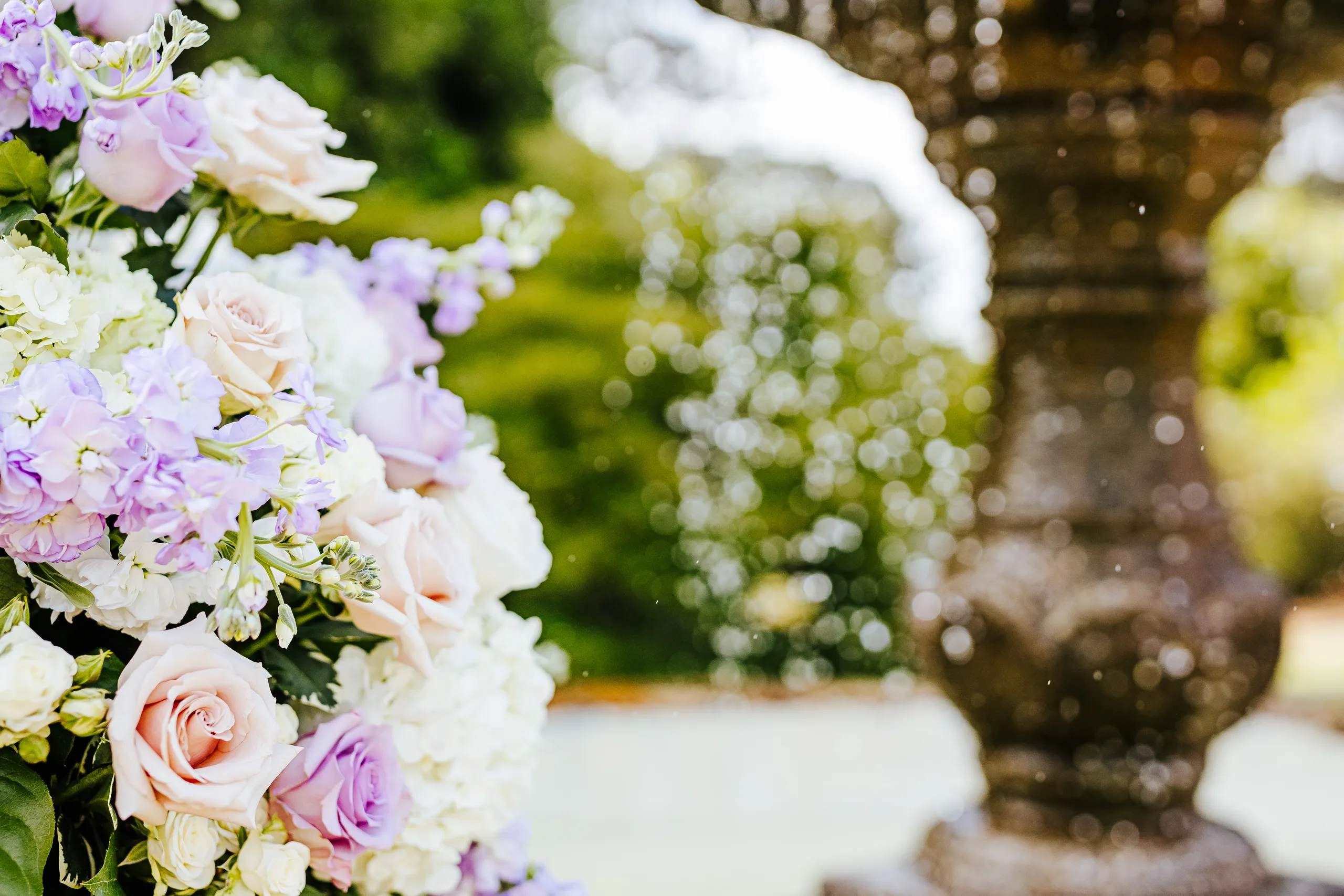 Wedding Florals: lavender flowers beside the fountain at a wedding at the Country Club of Roswell in Roswell, GA