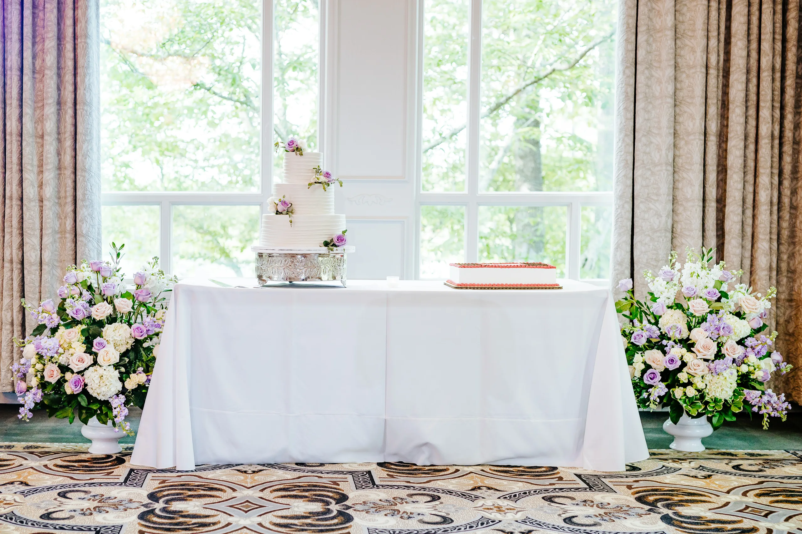 Reception Details: the cake table with flowers on each side at a wedding at the Country Club of Roswell in Roswell, GA