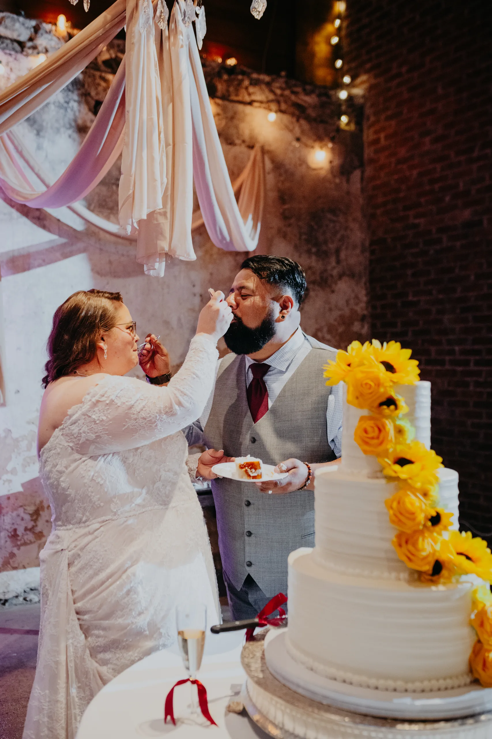 Wedding Cake Details: cutting the sunflower cake and feeding each other, at their wedding at 550 Trackside in Lawrenceville, GA