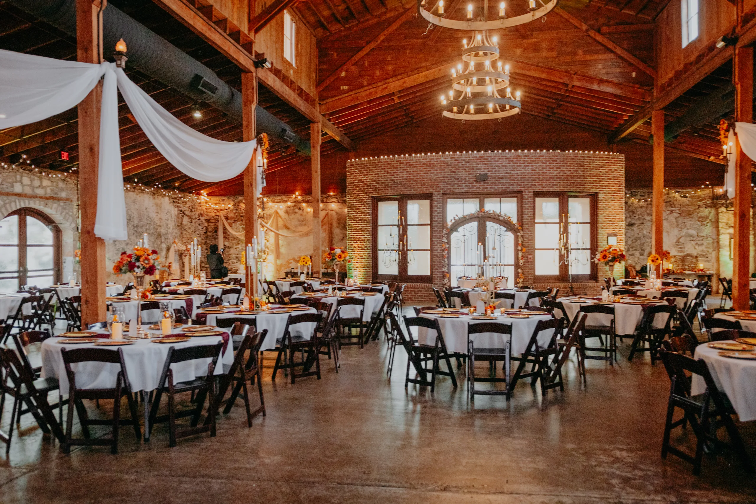 Reception Details: the reception room set under the wood ceilings and chandeliers, at a wedding at 550 Trackside in Lawrenceville, GA