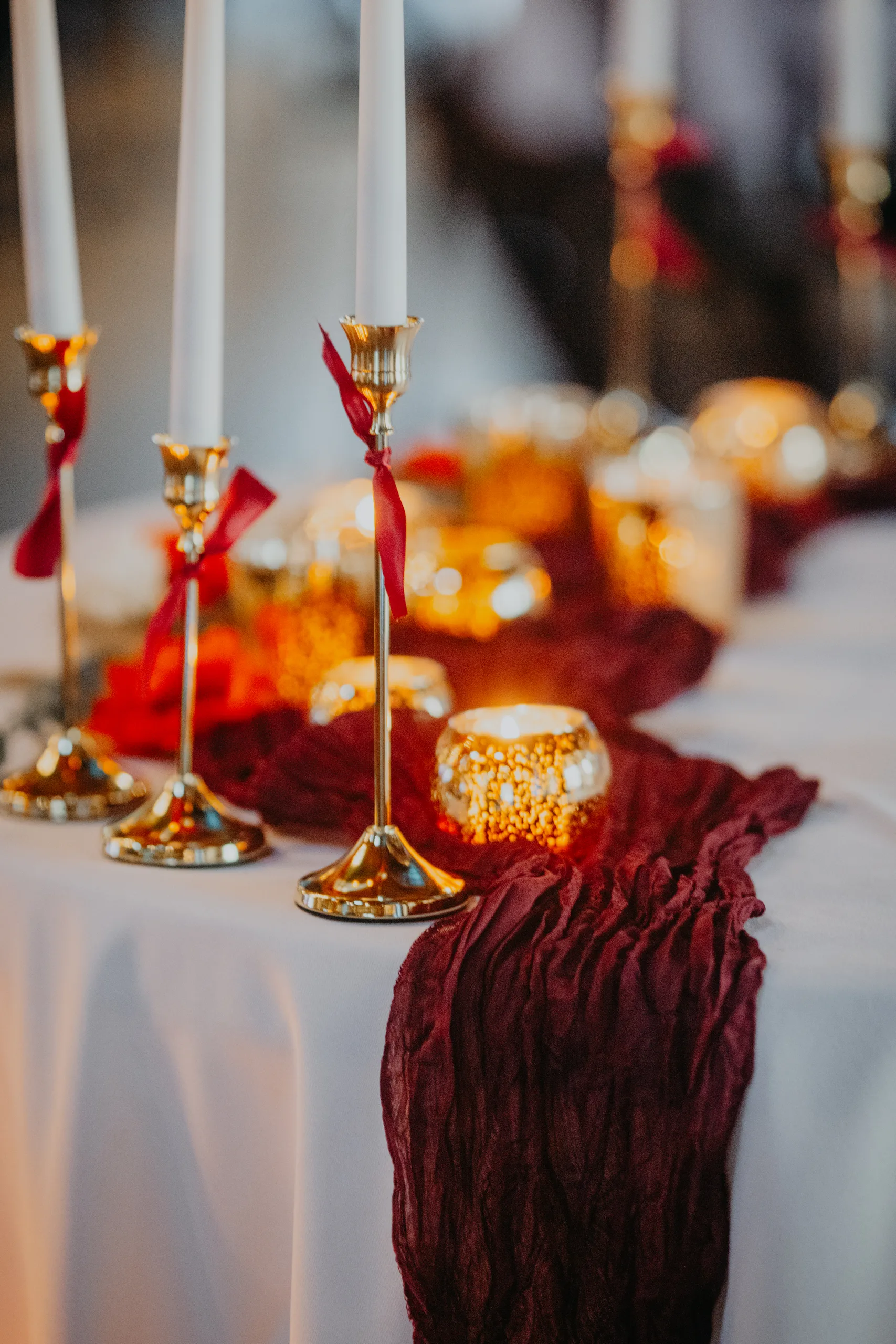 Reception Details: gold candlesticks and a burgundy runner on the table, at a wedding at 550 Trackside in Lawrenceville, GA