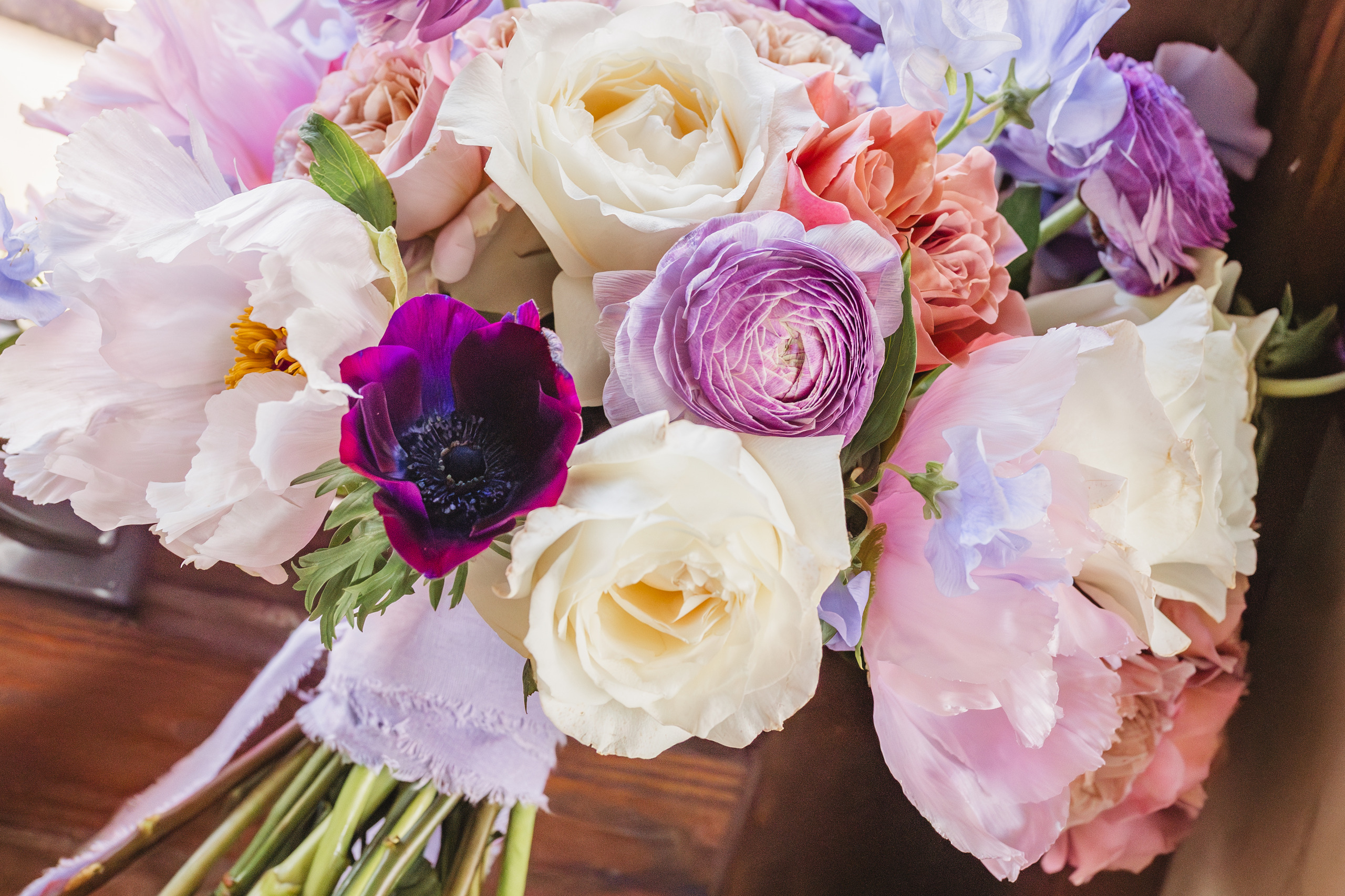 Wedding Florals: her bouquet of cream garden roses, lavender ranunculus and a deep purple anemone, at a wedding at Summerour Studio in Atlanta, GA
