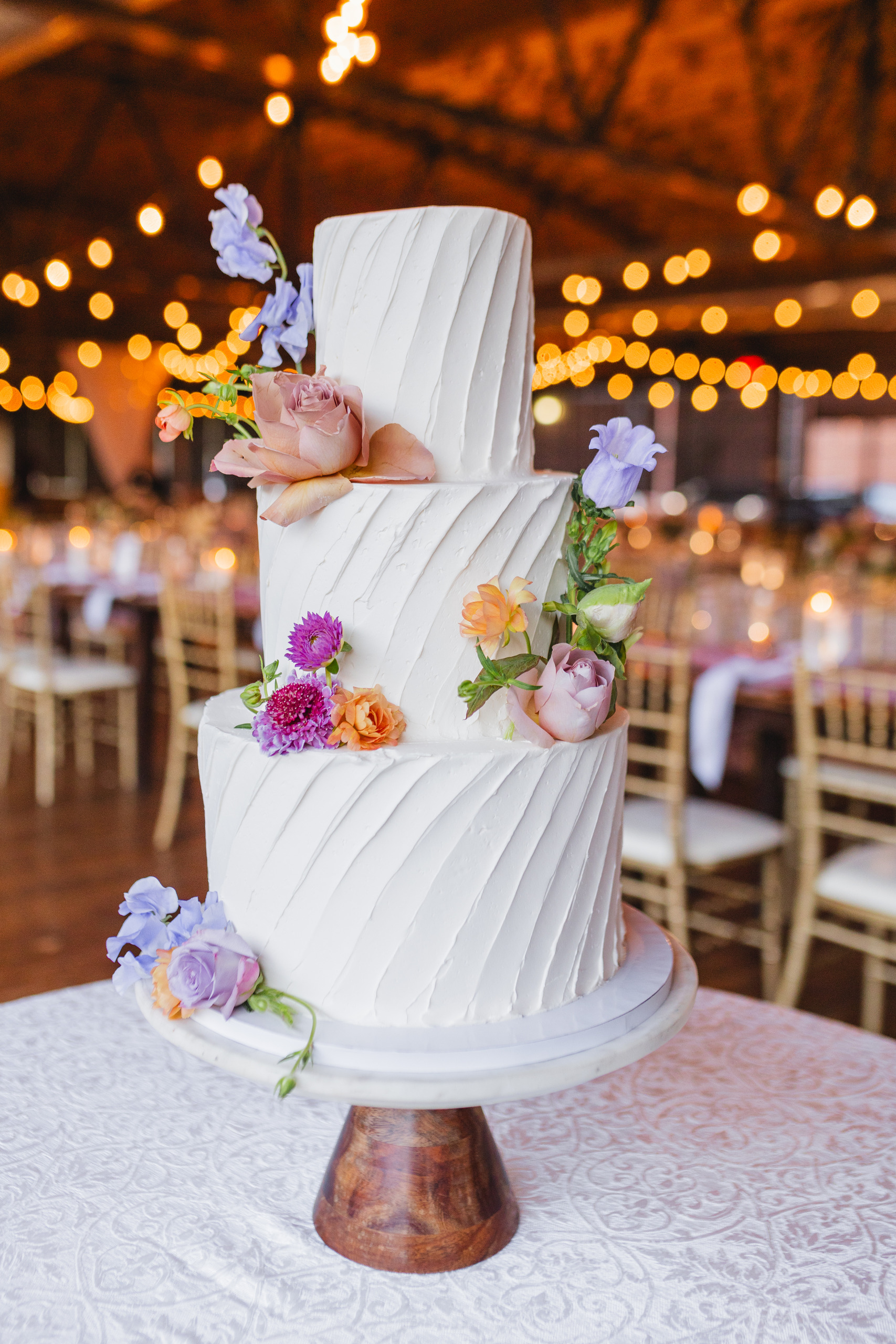 Wedding Cake: the three-tier combed buttercream cake dressed in lavender and peach blooms, at a wedding at Summerour Studio in Atlanta, GA