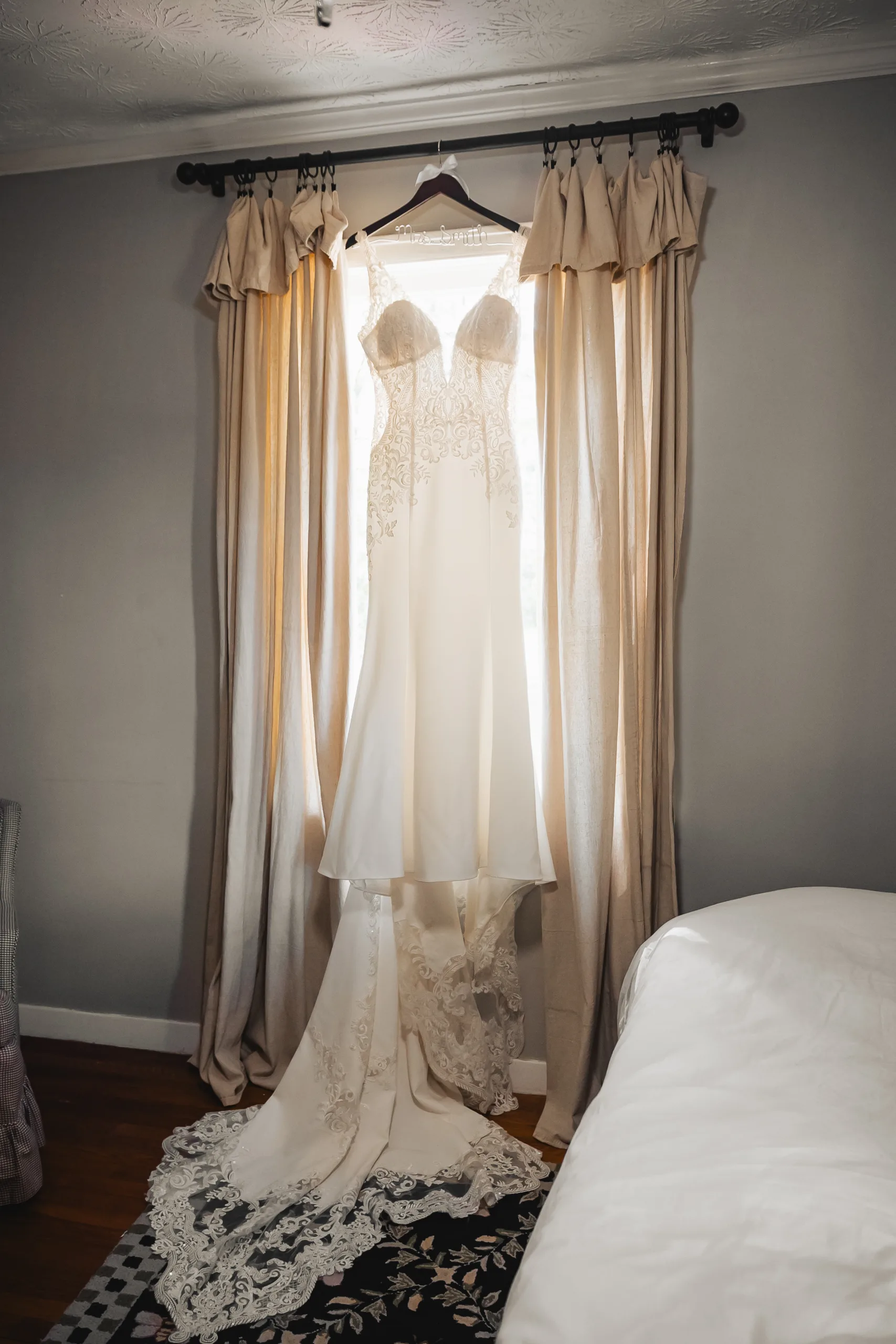 Wedding Details: her lace gown hanging in the window before their wedding at Ivy Hall at Roswell Mill in Roswell, GA