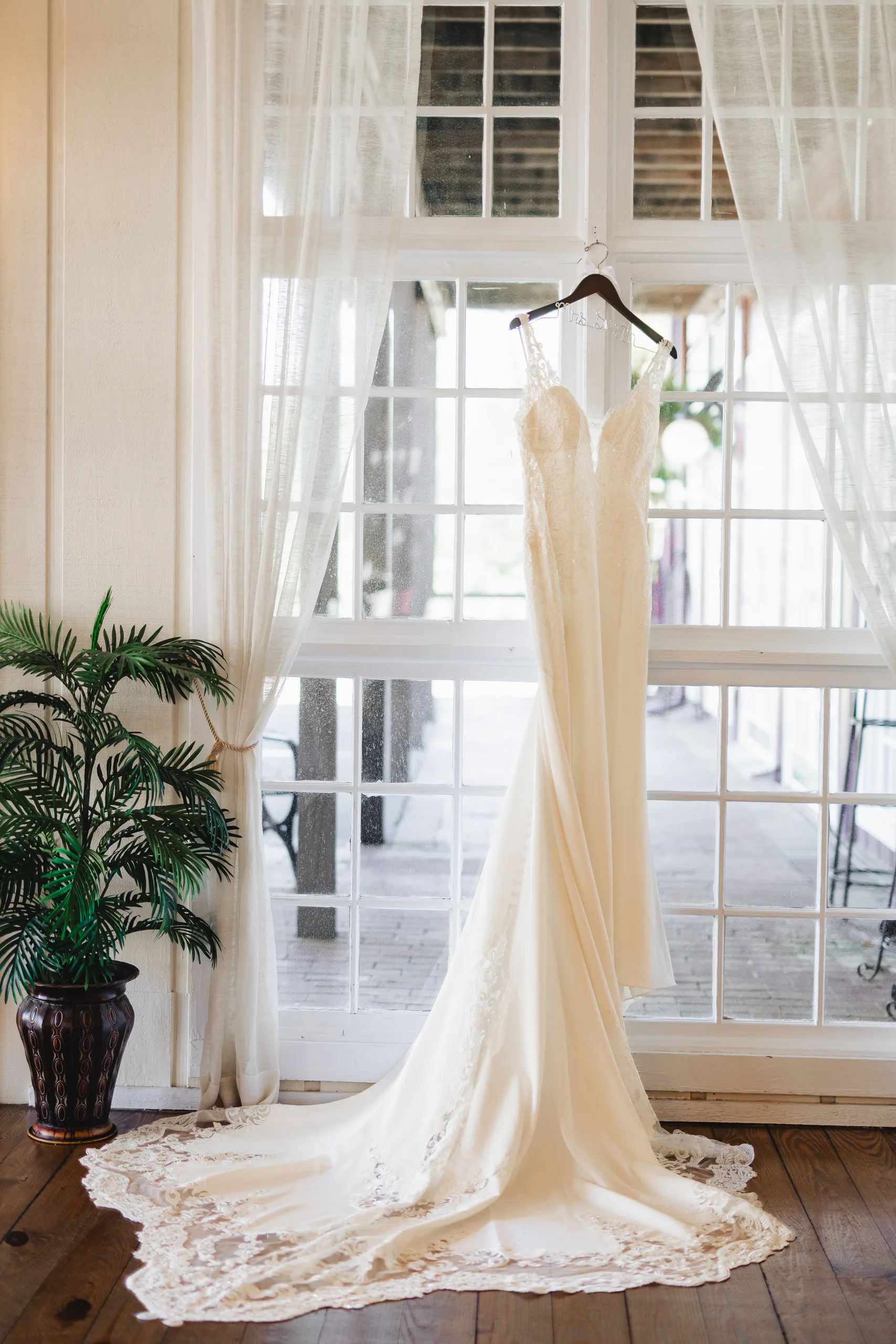 Wedding Details: her gown hanging in the tall windows of the bridal suite before their wedding at Ivy Hall at Roswell Mill in Roswell, GA
