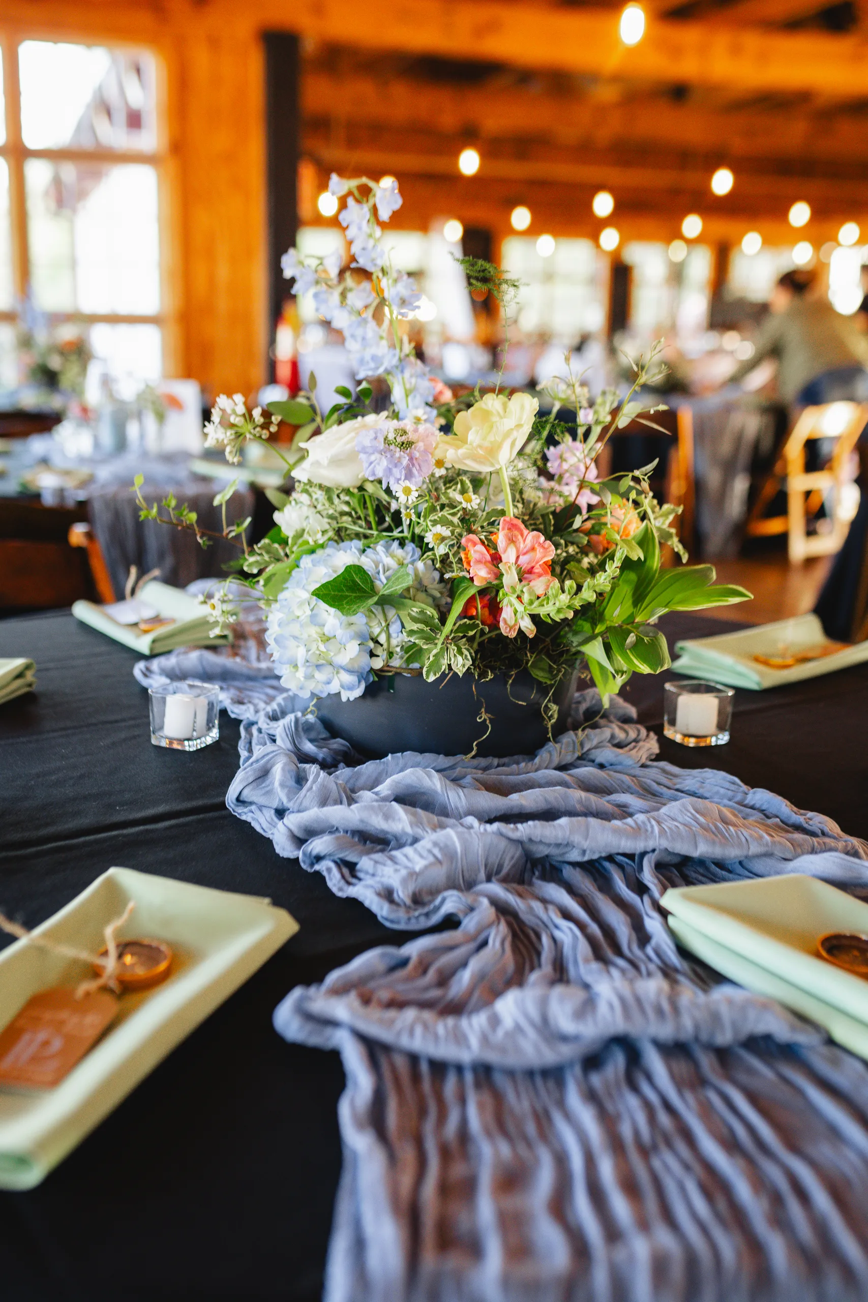 Reception Details: a centerpiece of pastel flowers on a dark tablecloth at a wedding at Ivy Hall at Roswell Mill in Roswell, GA