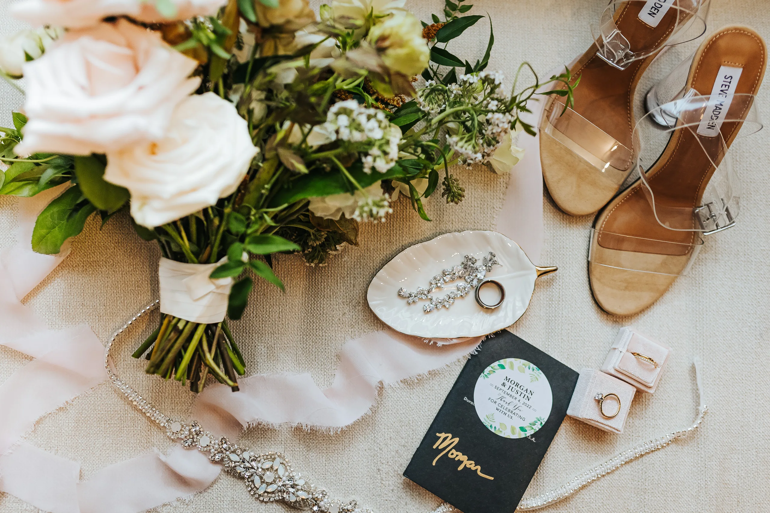 Wedding Details: her bouquet, heels, beaded belt, rings and vow book laid out, at a wedding at Terminus 330 in Atlanta, GA