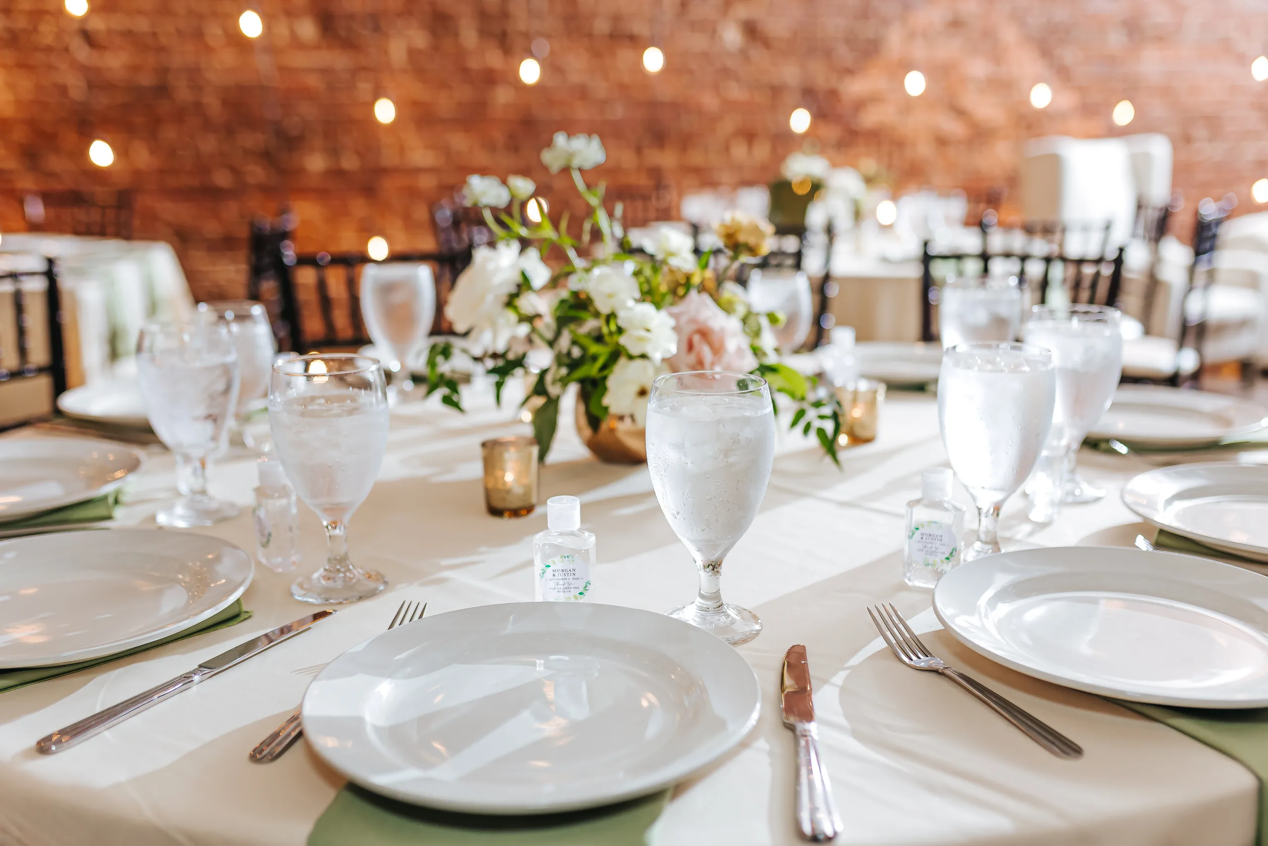 Reception Details: a table set with white florals and sage napkins, at a wedding at Terminus 330 in Atlanta, GA