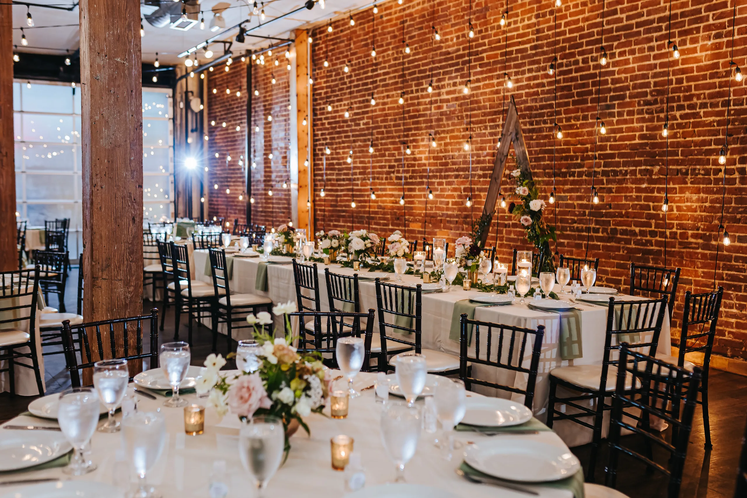 Reception Details: the reception room set under string lights along the brick wall, at a wedding at Terminus 330 in Atlanta, GA