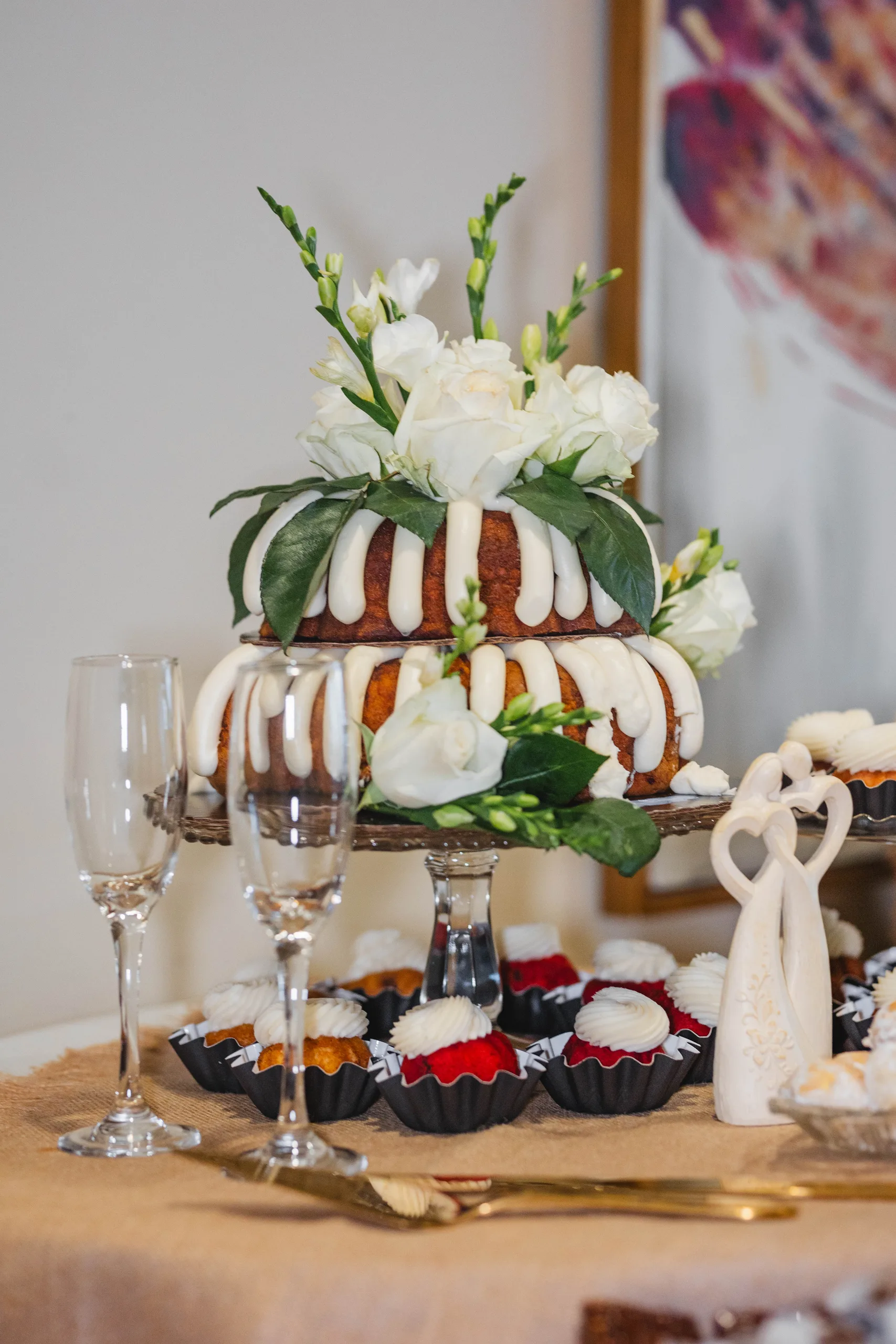 Wedding Cake Details: the tiered bundt cake dressed with white roses, bundtinis all around it, at a wedding at Naylor Hall in Roswell, GA