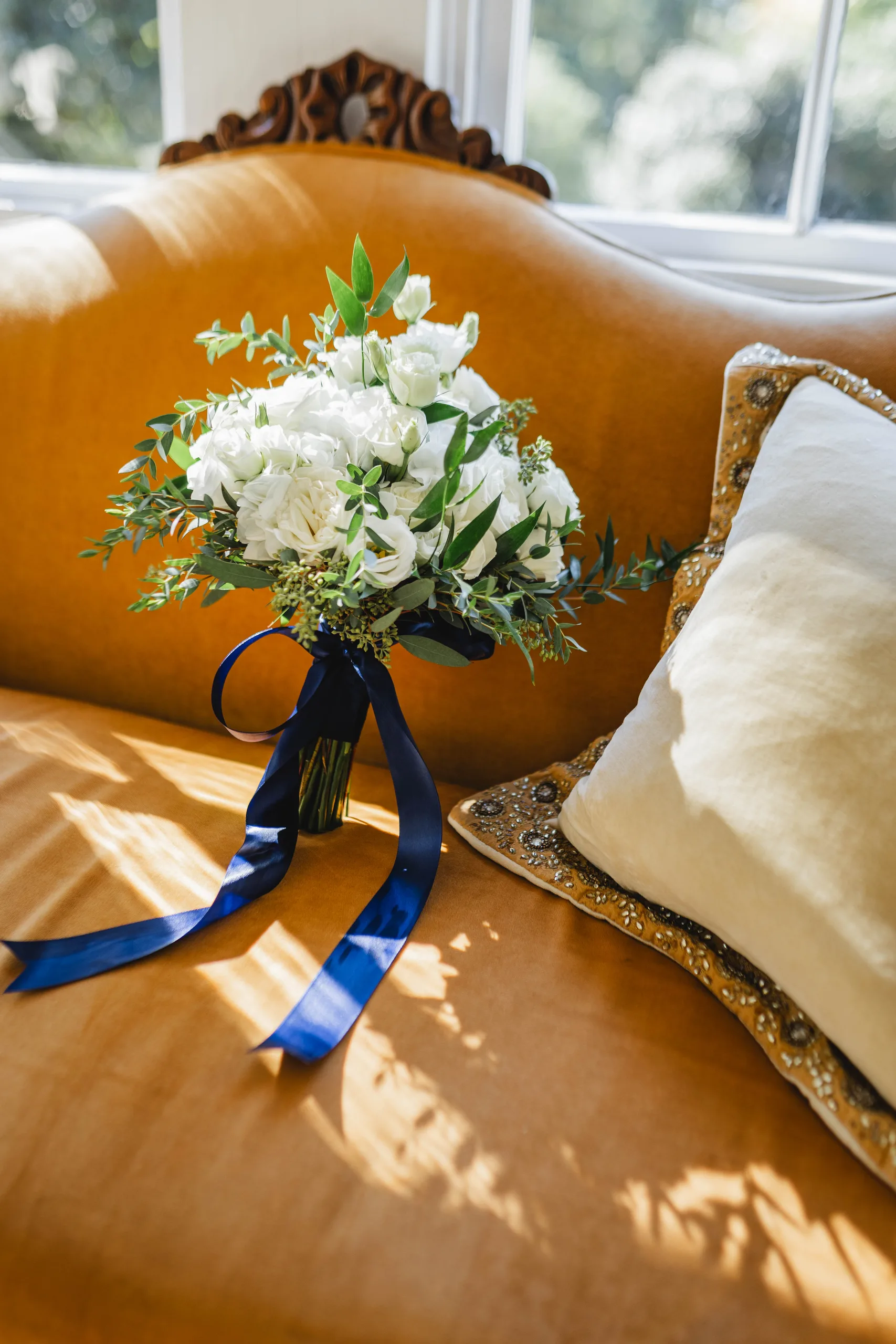 Wedding Florals: her bouquet with its navy ribbon on the gold settee, at a wedding at Naylor Hall in Roswell, GA