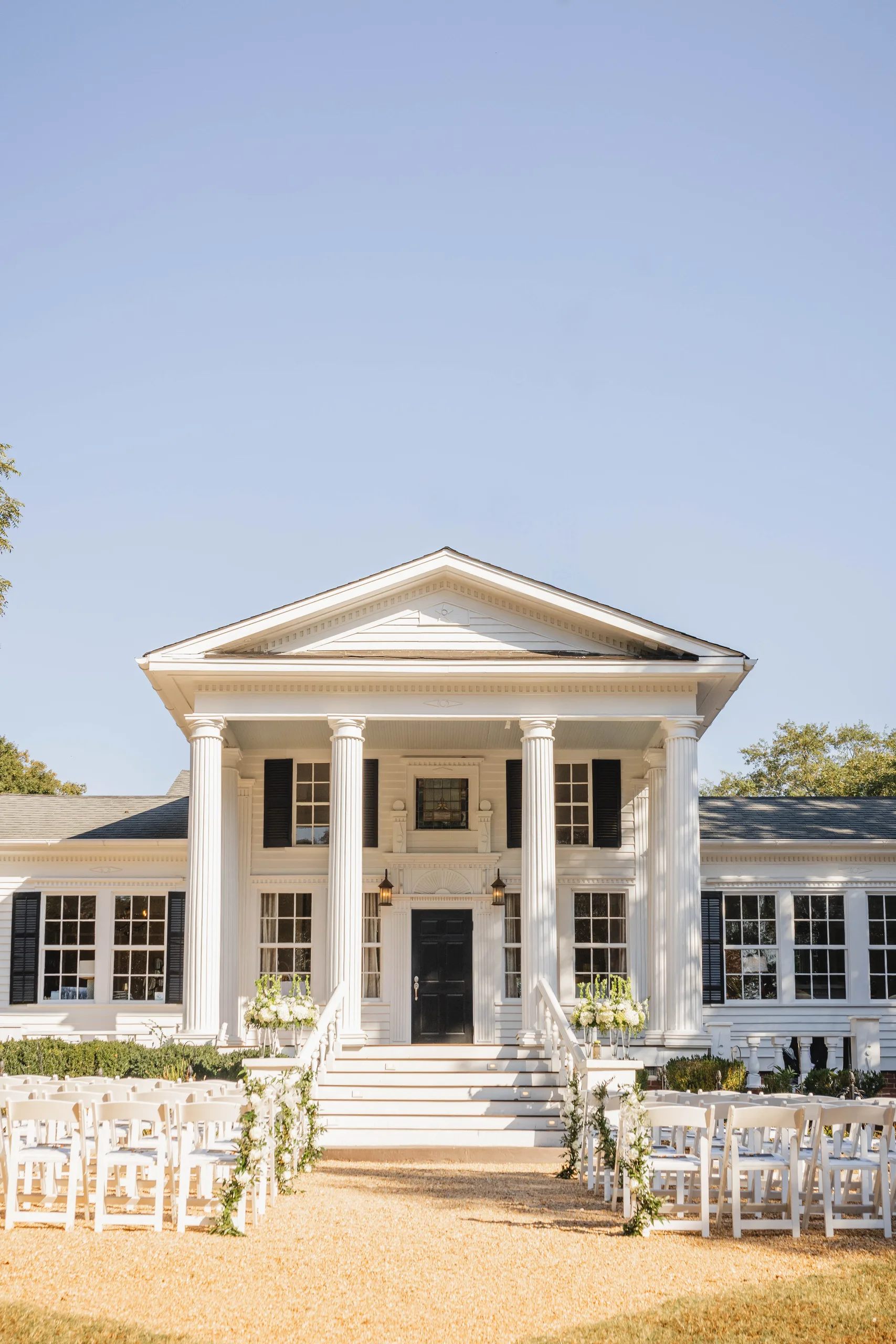 Wedding Ceremony: the white columns and front steps, chairs set out on the lawn, at a wedding at Naylor Hall in Roswell, GA
