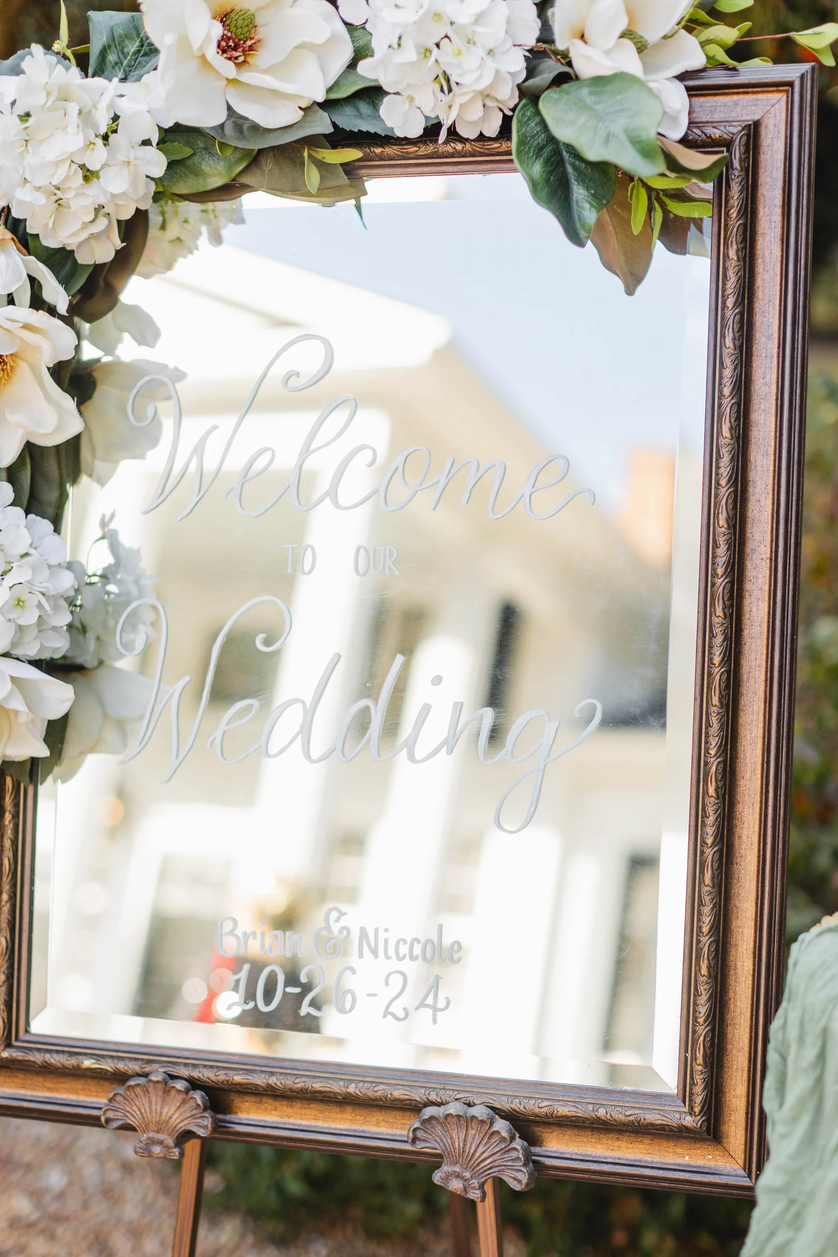 Wedding Details: the welcome mirror framed in magnolias, at a wedding at Naylor Hall in Roswell, GA