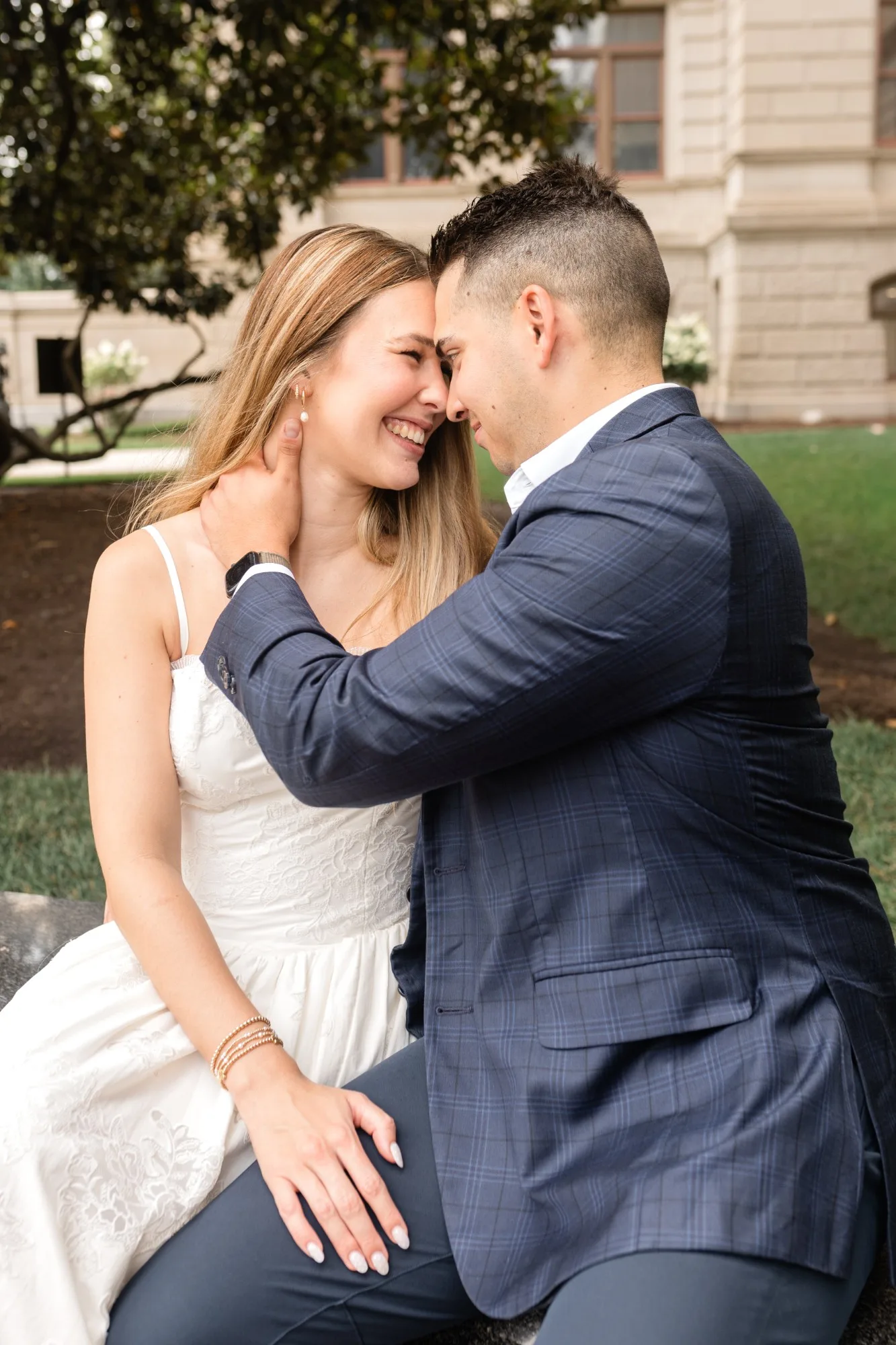 Capitol Grounds: foreheads together and laughing under a magnolia tree, at their engagement session at the Georgia State Capitol in Atlanta, GA
