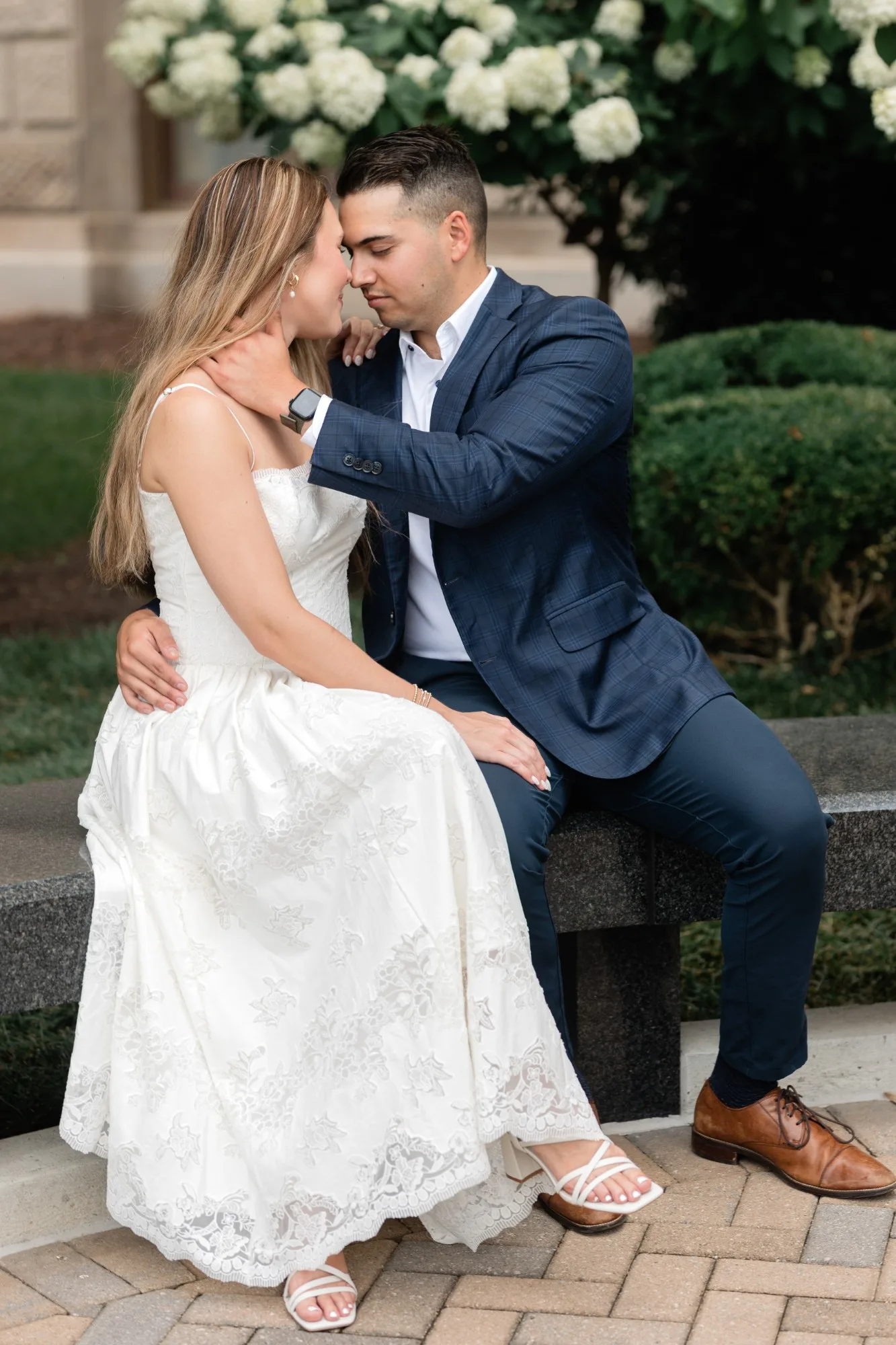 Capitol Grounds: nose to nose on the granite bench, the hydrangeas behind them, at their engagement session at the Georgia State Capitol in Atlanta, GA