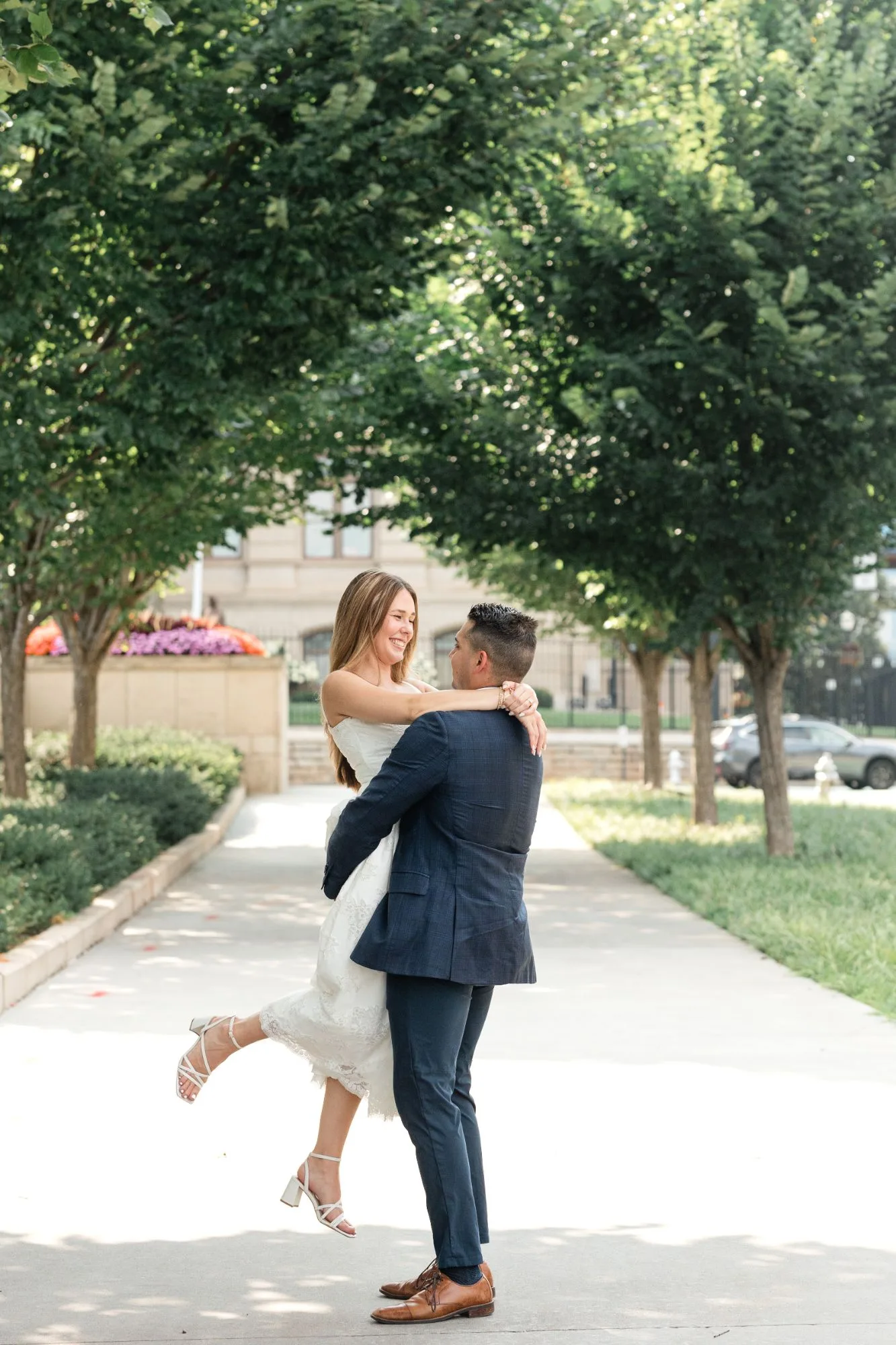 Capitol Grounds: he lifts her on a tree-lined sidewalk, her heel kicked up, at their engagement session at the Georgia State Capitol in Atlanta, GA