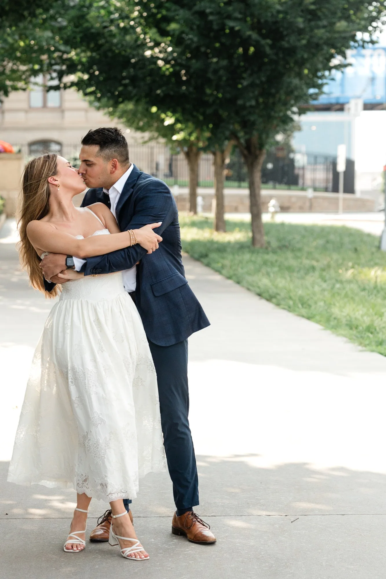 Capitol Grounds: a kiss on the tree-lined sidewalk, at their engagement session at the Georgia State Capitol in Atlanta, GA