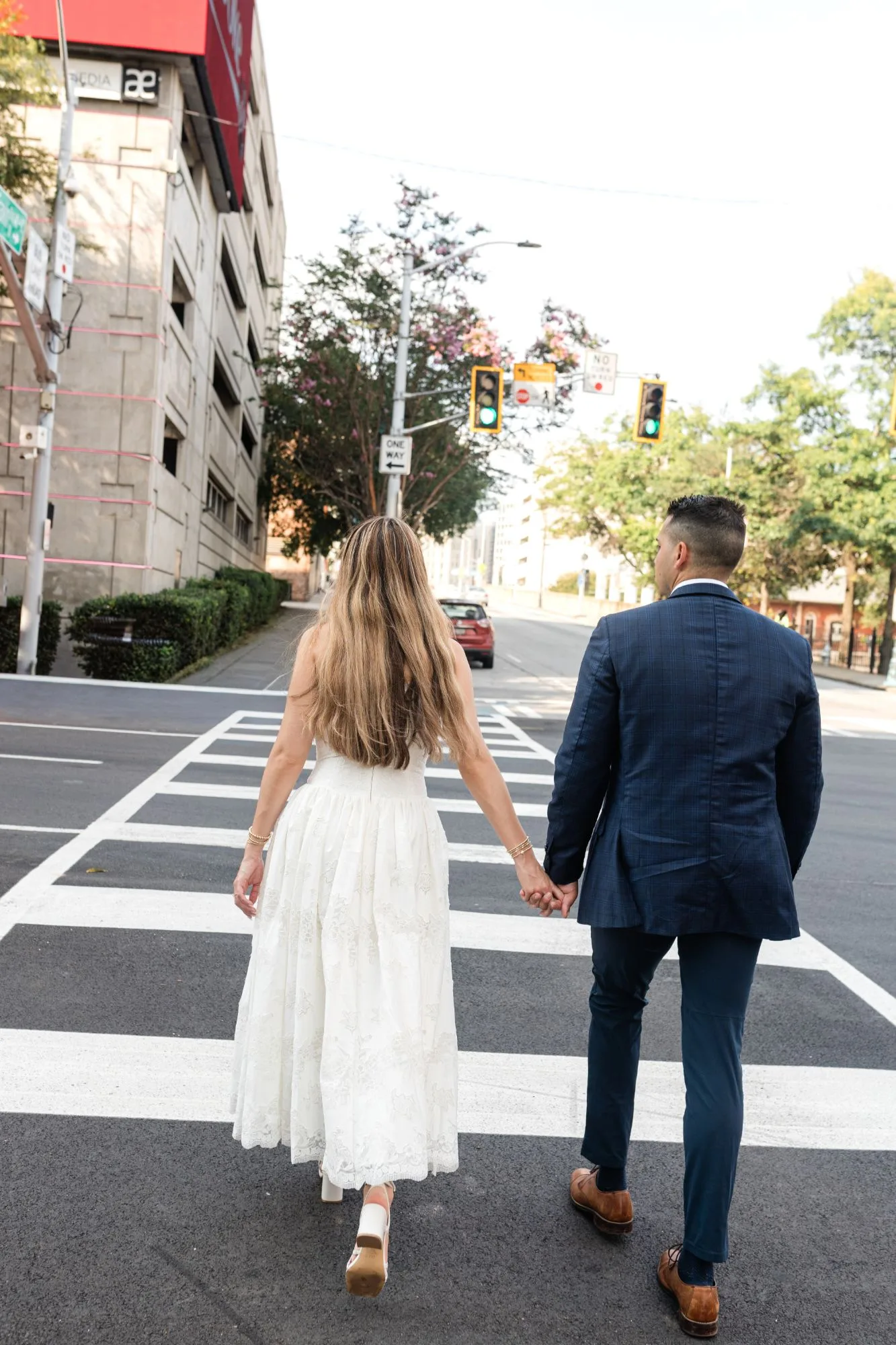 Downtown Atlanta: walking away hand in hand across the crosswalk, at their engagement session near the Georgia State Capitol in Atlanta, GA