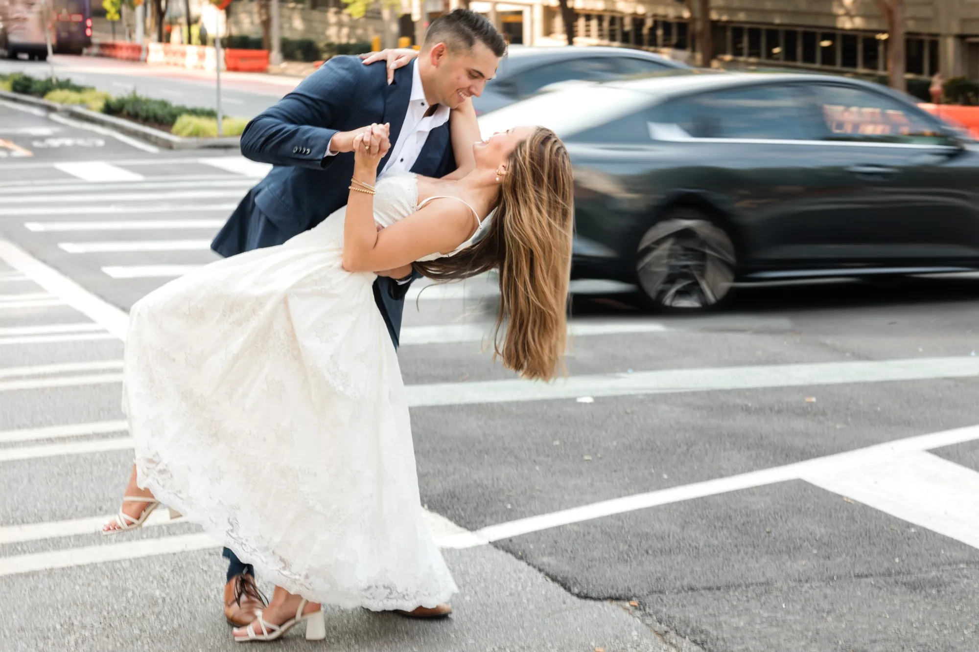 Downtown Atlanta: a dip in the crosswalk as a car blurs past, at their engagement session near the Georgia State Capitol in Atlanta, GA
