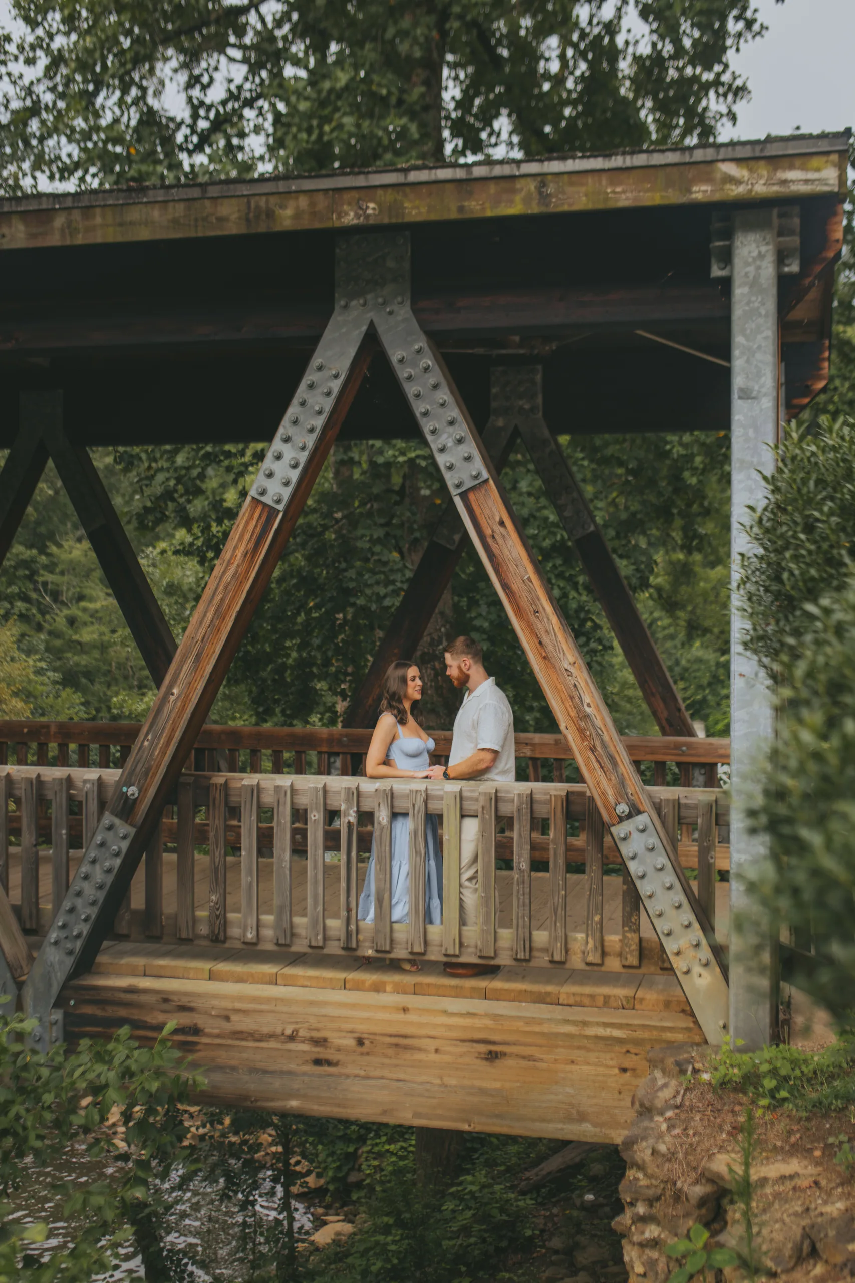 Engagement: the two of them on the covered bridge seen from below, at their engagement session at Roswell Mill in Roswell, GA