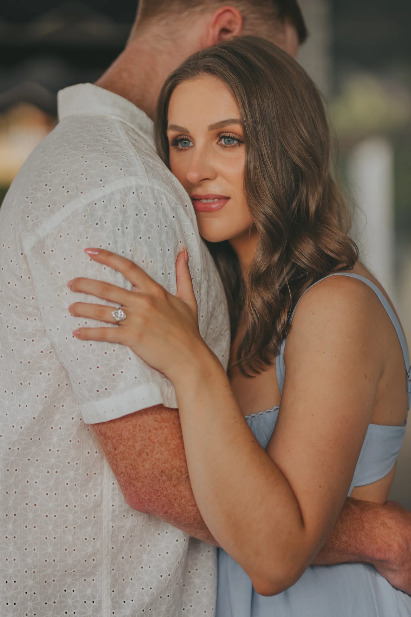 Engagement Ring: her ring on his shoulder as they hug, at their engagement session on Roswell Square in Roswell, GA