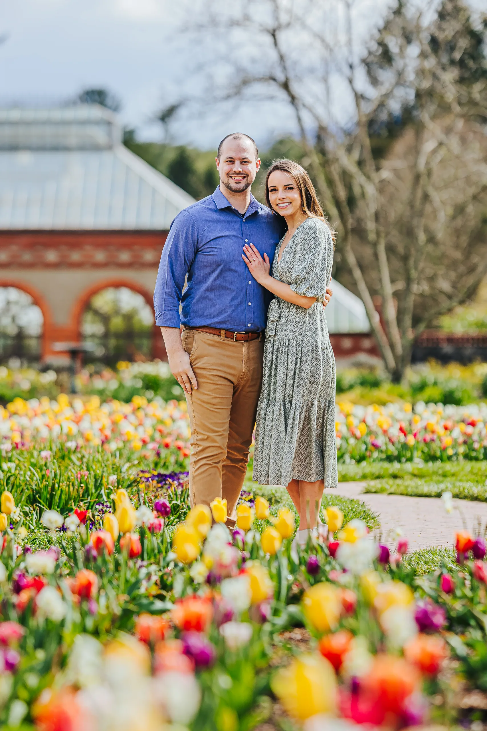 Walled Garden: standing together in the tulips in front of the Conservatory, at their engagement session at Biltmore Estate in Asheville, NC