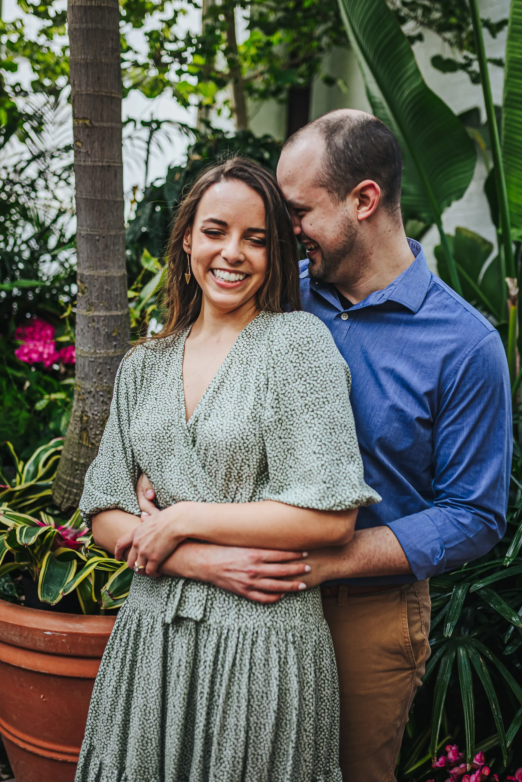 Conservatory: laughing together among the palms and pink blooms, at their engagement session at Biltmore Estate in Asheville, NC