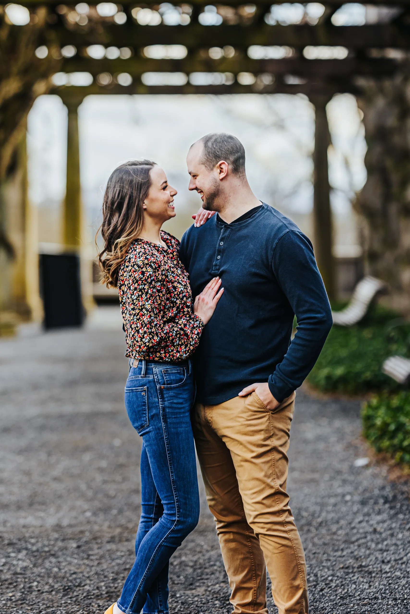 Pergola: smiling at each other on the gravel path under the pergola, at their engagement session at Biltmore Estate in Asheville, NC