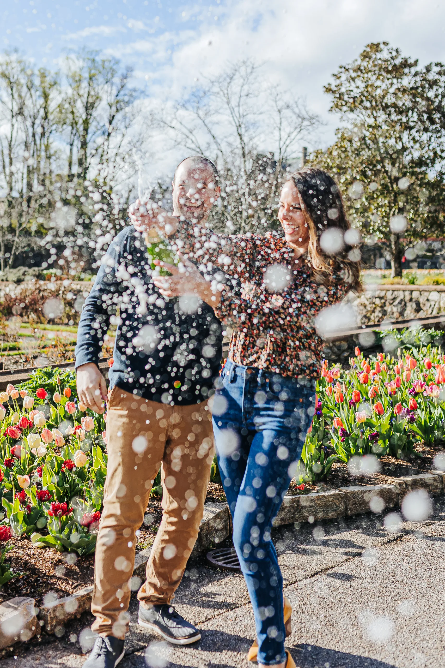 Walled Garden: champagne spraying all around them, laughing, at their engagement session at Biltmore Estate in Asheville, NC