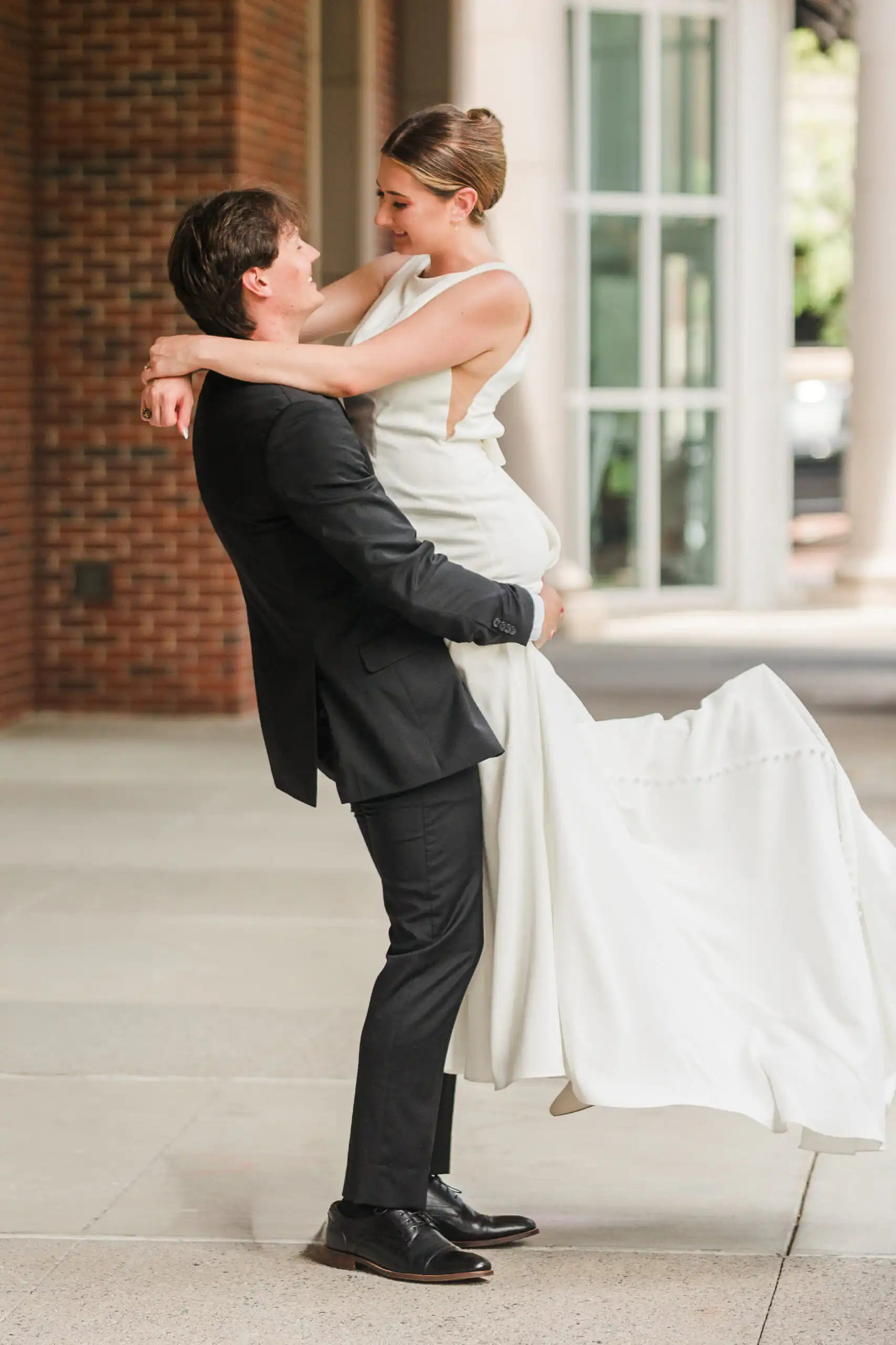 Wedding Formals: the groom lifting her up, her train swinging out, at their elopement at Alpharetta City Hall in Alpharetta, GA