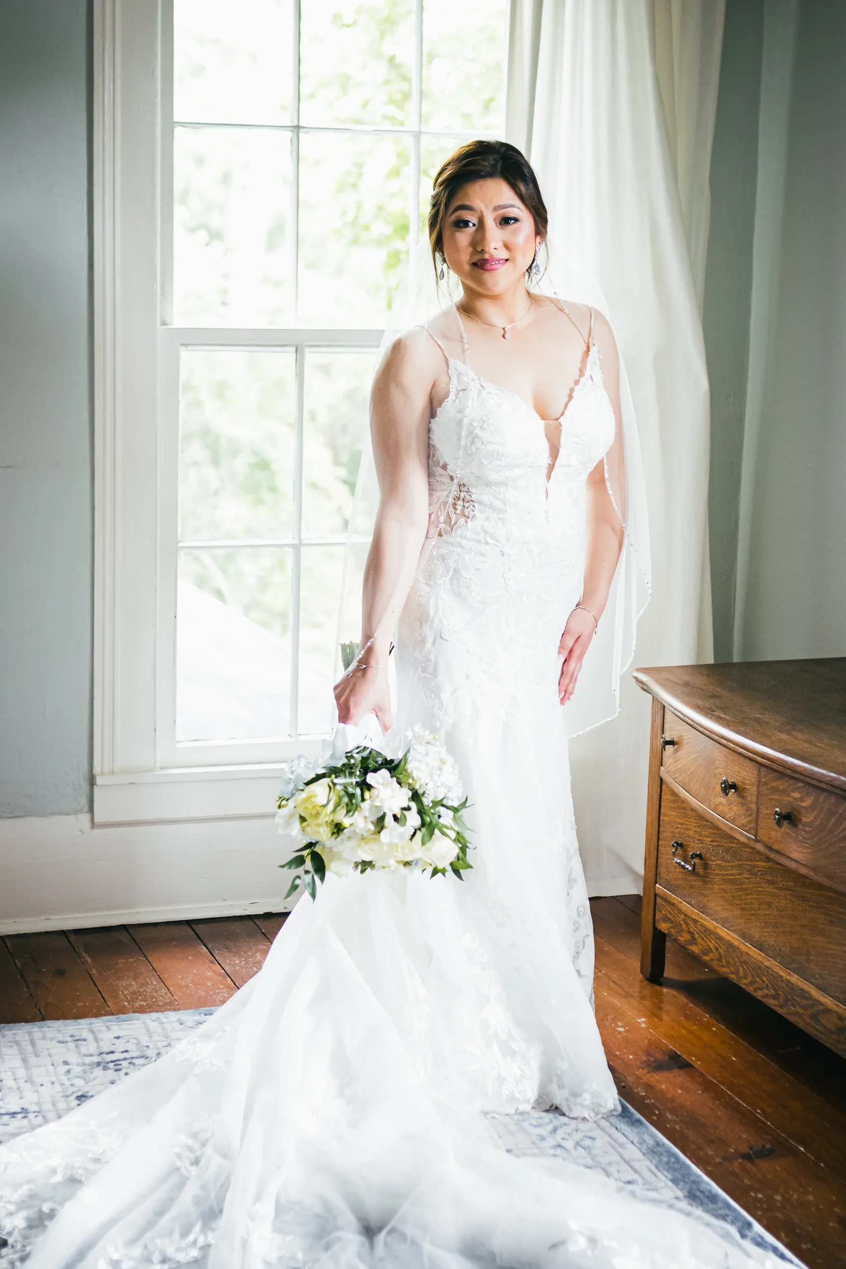 Bridal Portraits: the bride by the window with her bouquet at their wedding at the Payne-Corley House in Duluth, GA