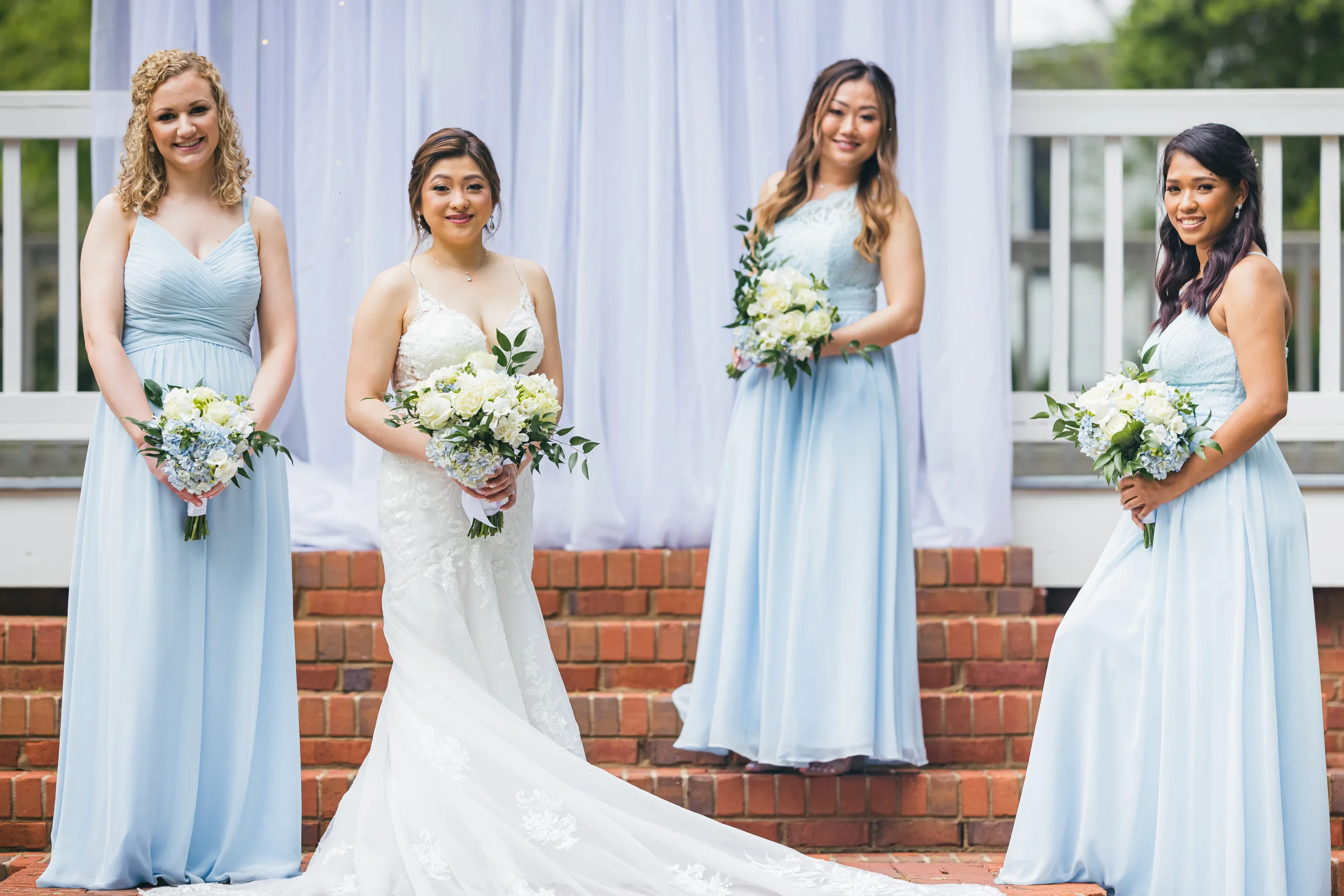 Wedding Party: the bride with her bridesmaids in light blue by the arch at their wedding at the Payne-Corley House in Duluth, GA